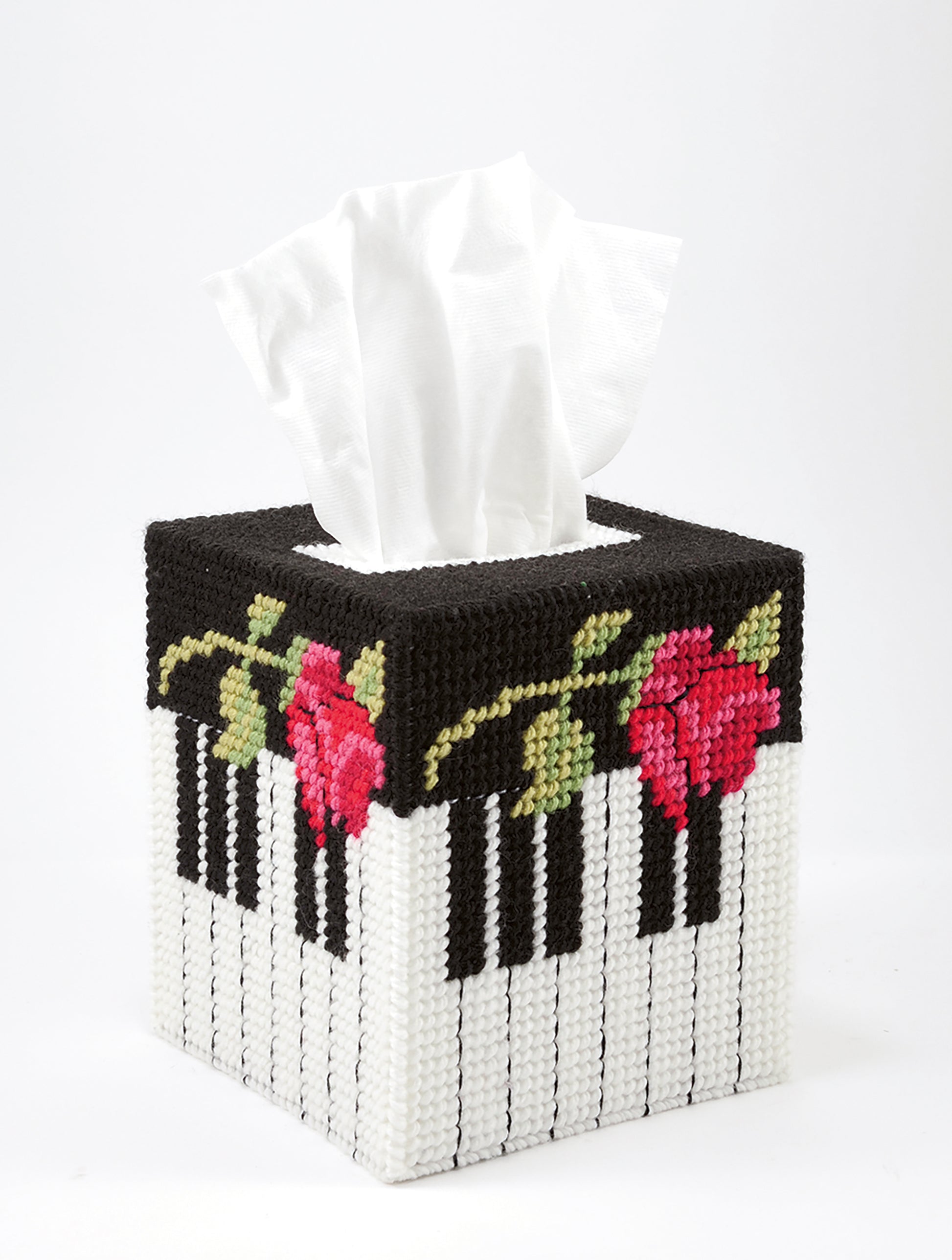 From Leisure Arts, "Tissue Box Covers—8 Projects to Brighten Up Any Room in Your Home" features creative designs like a piano key motif with red roses, crafted using plastic canvas patterns and worsted weight yarn.