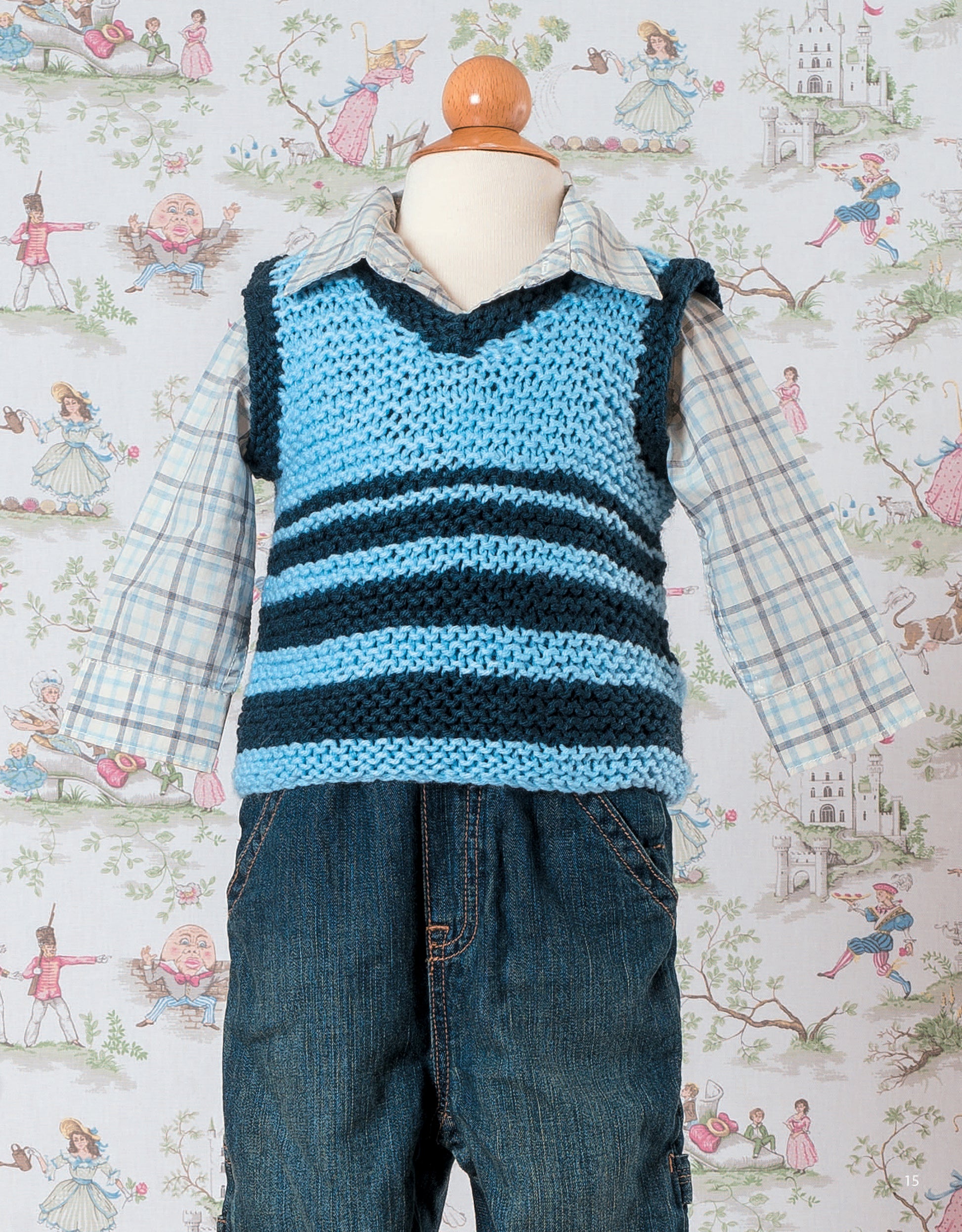 A child mannequin models an outfit featuring a garter stitch knitted vest from Garter Stitch for Baby by Leisure Arts, layered over a plaid shirt and jeans—set amid fairy tale wallpaper, it’s perfect inspiration for beginner knitters.