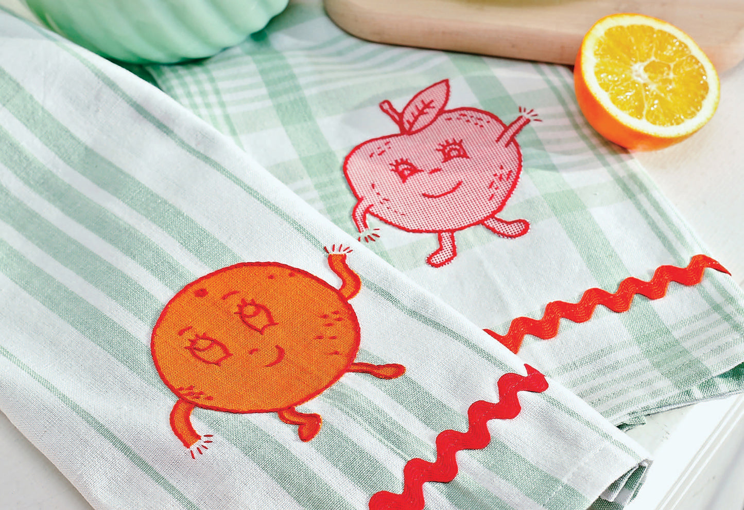 Learn to Embroider with the Best of Leisure Arts by Leisure Arts includes beginner-friendly projects like cheerful green and white striped dish towels featuring smiling cartoon orange and apple designs—ideal for adding monogramming to your kitchen decor.