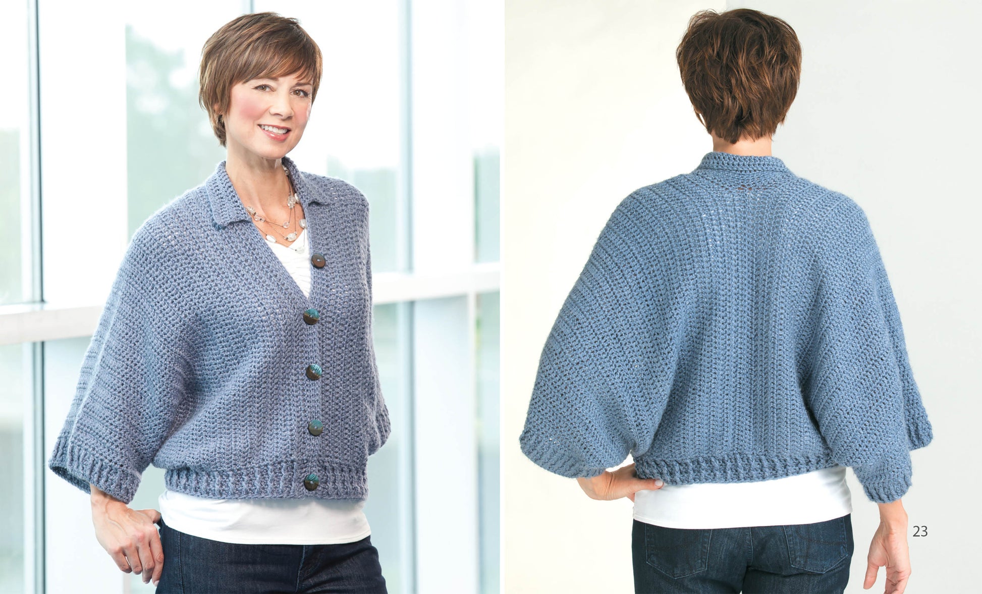 A woman with short brown hair models the Cuffed Shawl from "Crochet the Cuffed Shawl & More" by Leisure Arts, styled with a white shirt and dark jeans. She stands indoors, showing both front and back of the hand-crocheted piece.