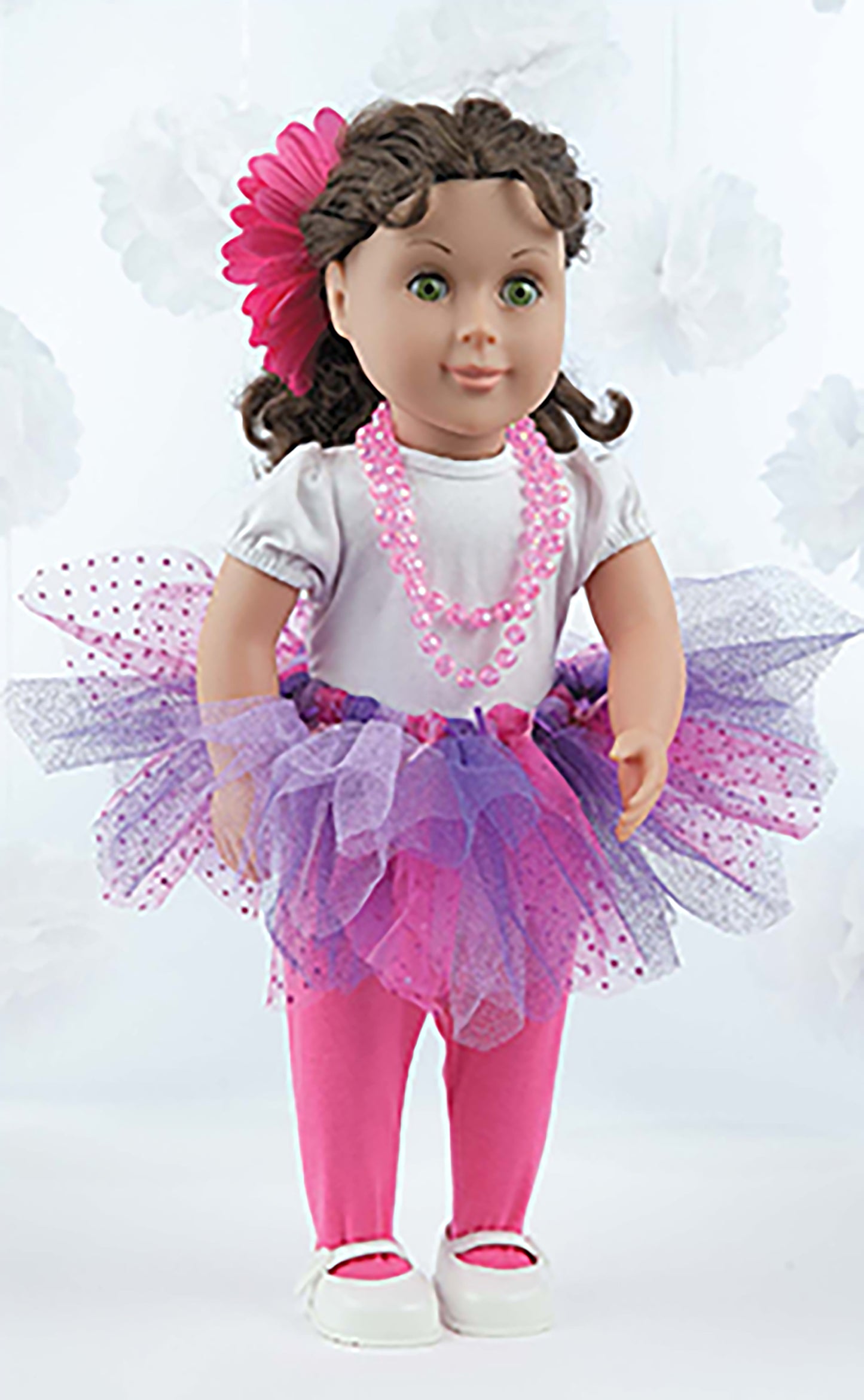 The "A Tutu for Every Occasion" doll by Leisure Arts features brown hair, green eyes, a pink flower headband, white shirt, pink beaded necklace, purple and pink no-sew tutu, pink leggings, and white shoes against a light backdrop.