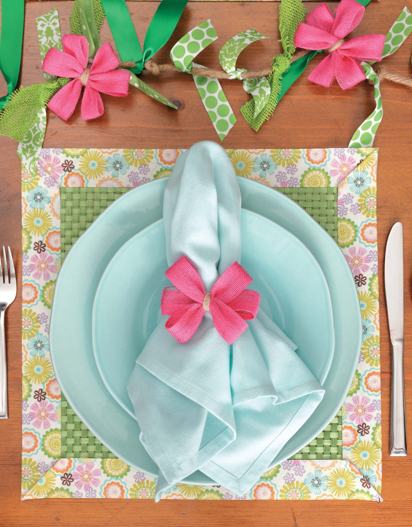 The table features a pastel blue plate set with a matching napkin and pink flower napkin ring on a floral placemat. "Decorate with Ribbon" by Leisure Arts adds pink and green ribbon crafts, perfect for beginner home decor enthusiasts.