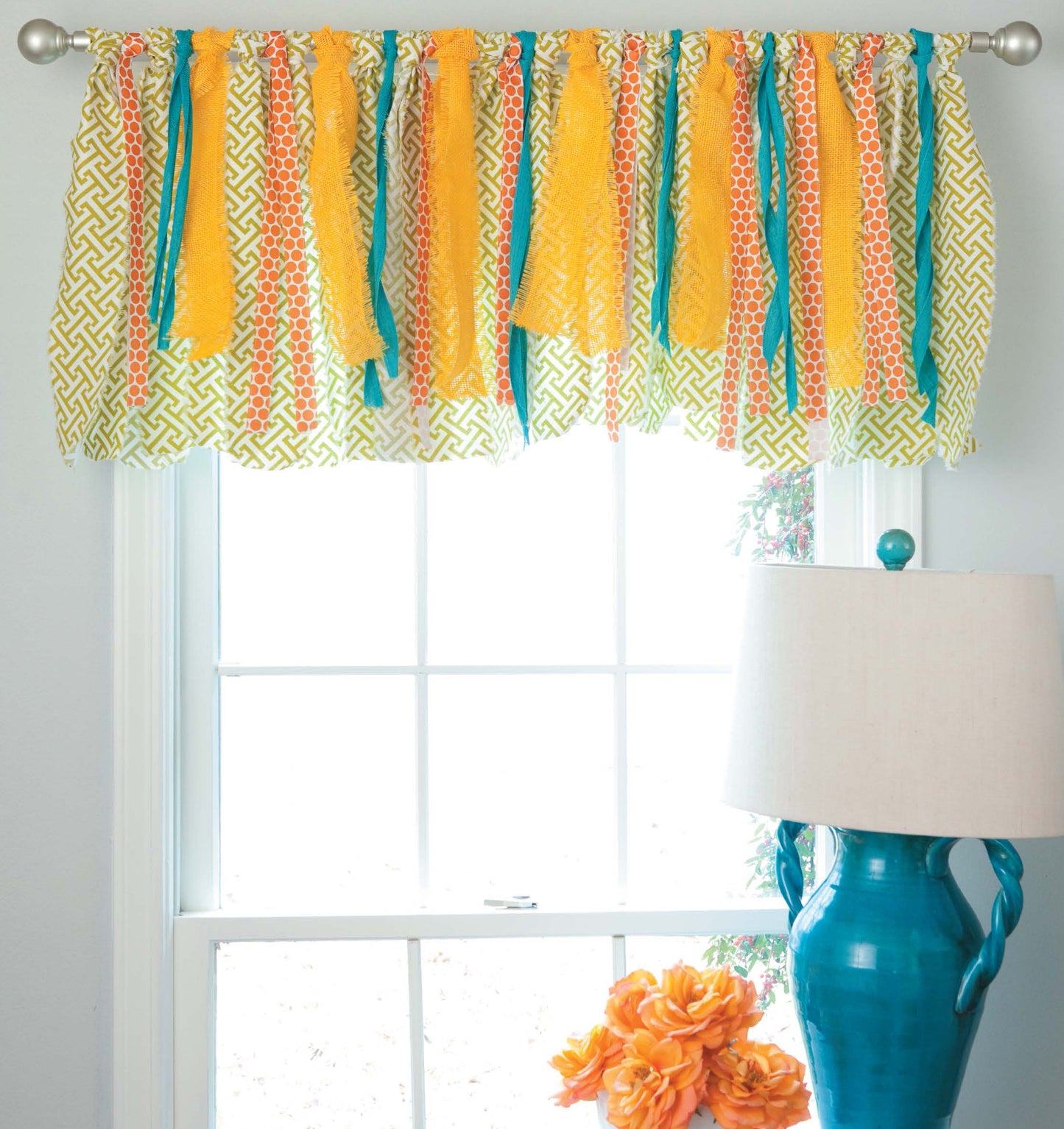 Decorate with Ribbon by Leisure Arts features a window curtain of yellow, orange, and turquoise fabric strips—an easy no-sew project. A turquoise lamp with orange flowers adds a cheerful touch, perfect for beginner home decor.