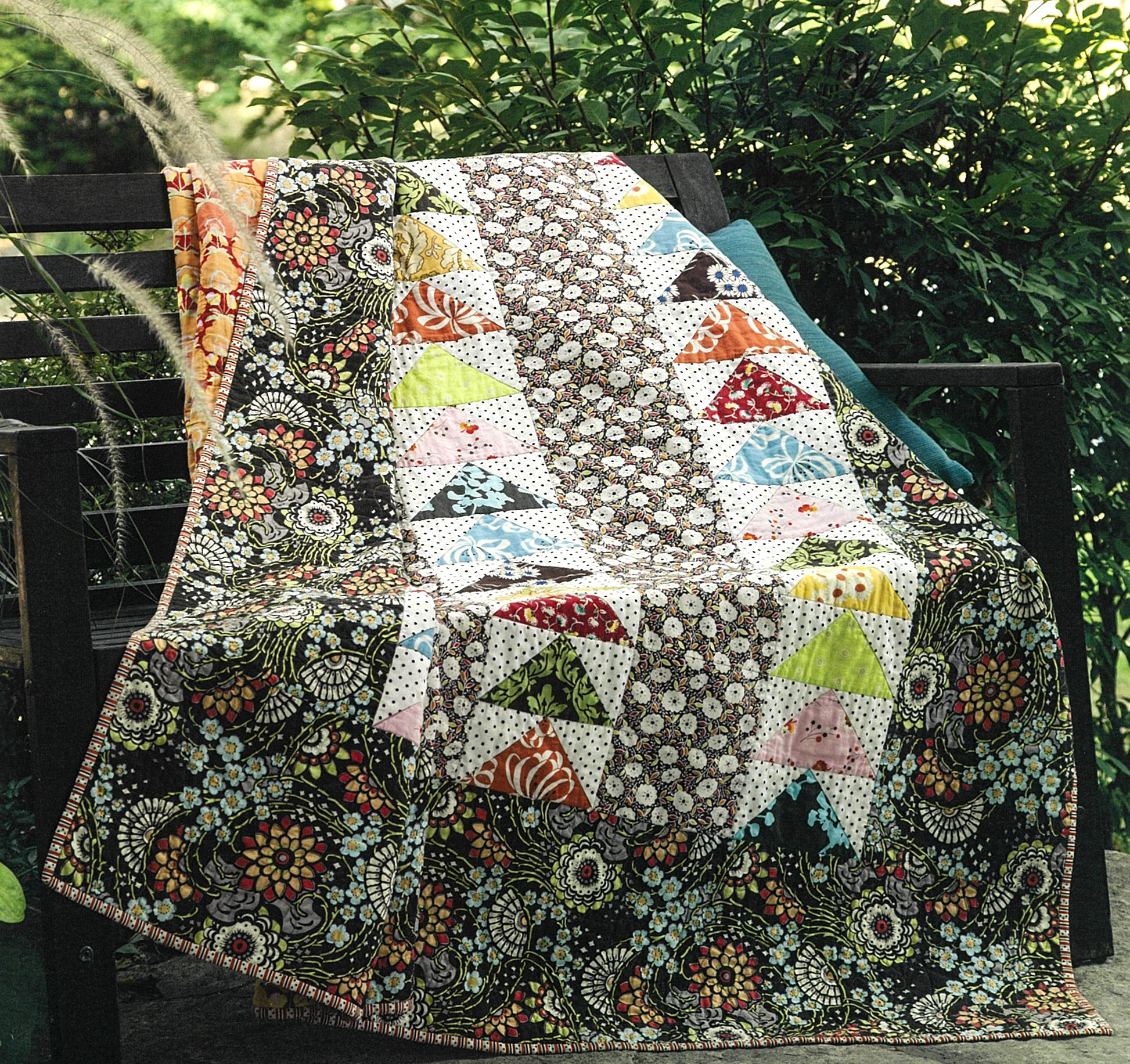 The Best of Quilty by Leisure Arts features a colorful quilt with floral and geometric patterns, draped over a wooden bench amid greenery—its decorative rows offer perfect inspiration for beginner or future embroidery projects.