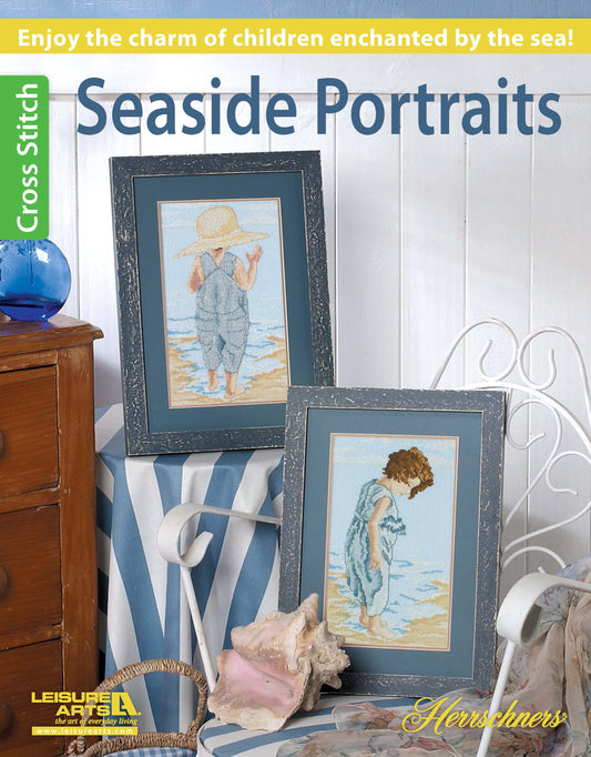 The Seaside Portraits Cross Stitch by Leisure Arts features two framed beach scenes of children—one in a straw hat and overalls, the other looking at the water—resting on a striped cloth with seashells for charming home decor.