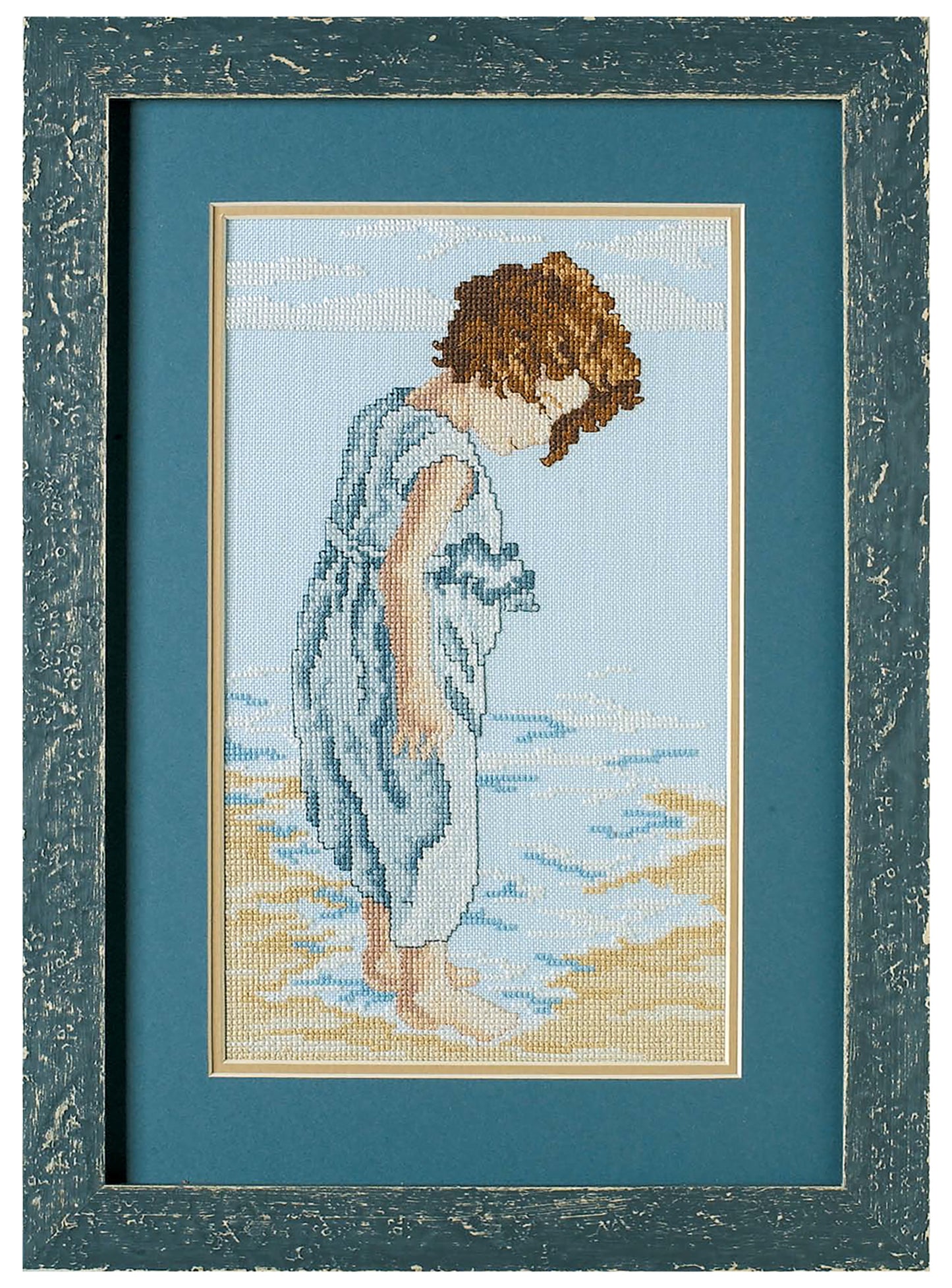 The Seaside Portraits Cross Stitch by Leisure Arts features a framed embroidery of a young child with curly brown hair in a blue dress on a sandy beach—an ideal home accent for anyone who loves beach scenes.