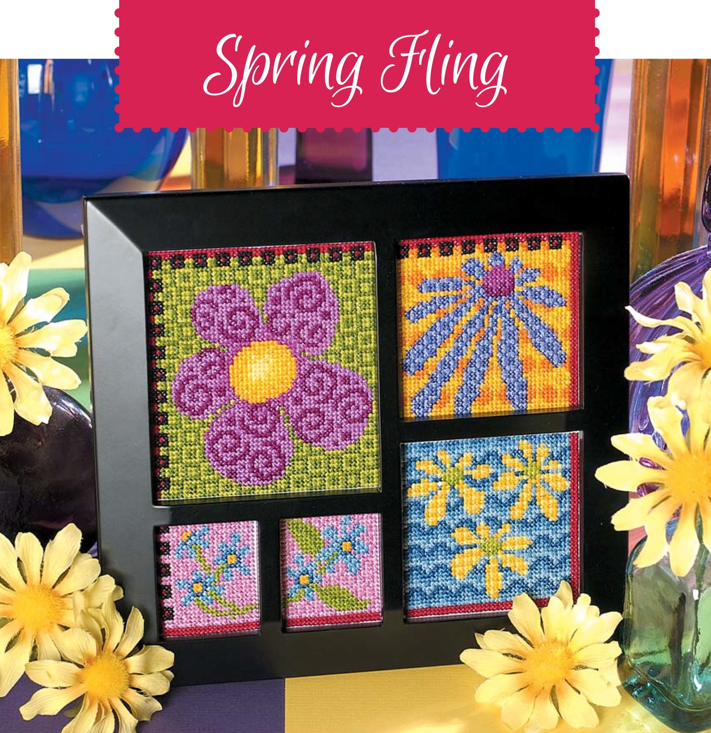 Leisure Arts’ Bright Blooms Cross Stitch features five colorful floral designs in a black frame, accented with yellow daisies and glass vases, "Spring Fling" scripted in white on a pink background.