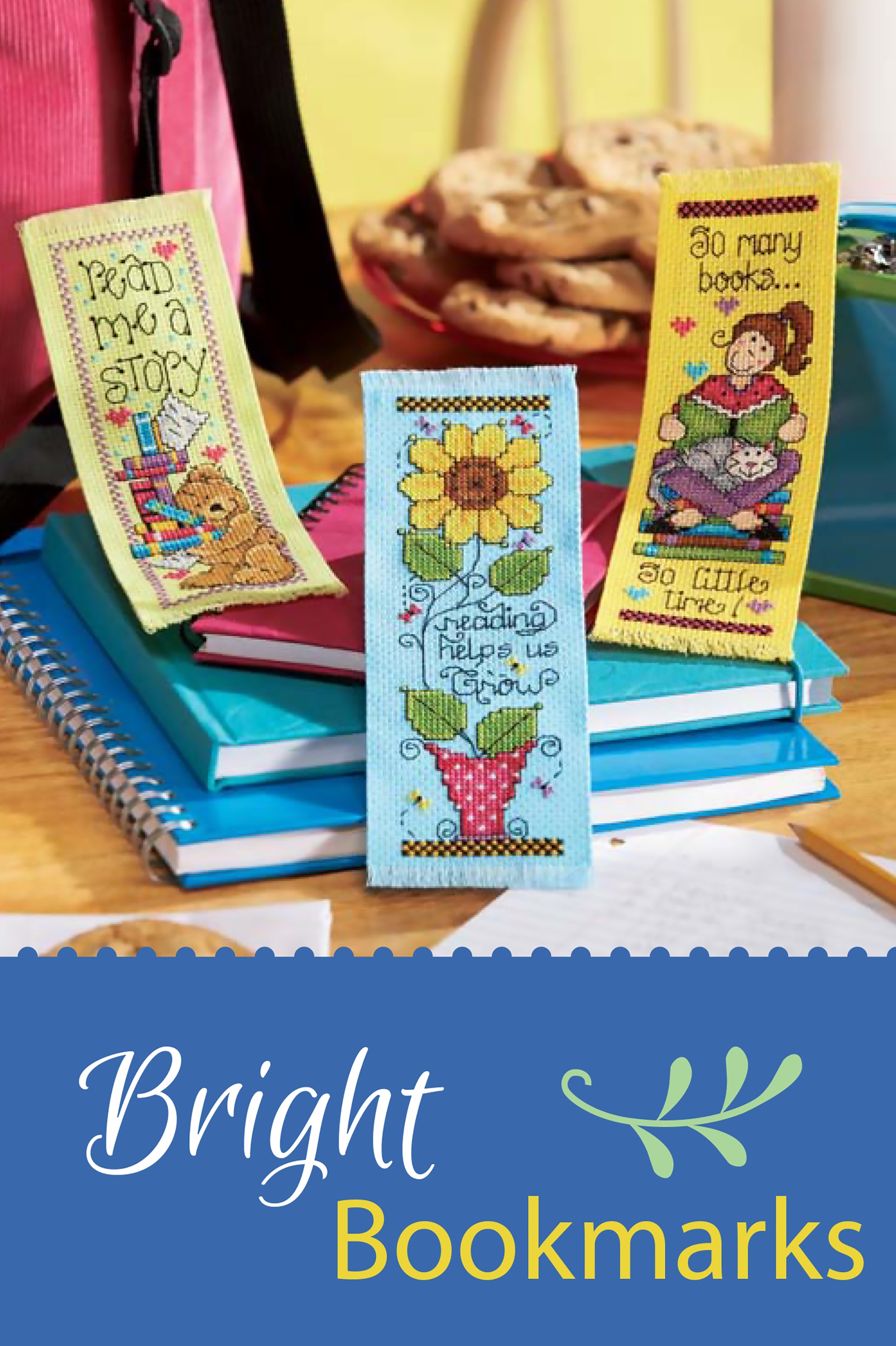 Three vibrant embroidered bookmarks from Leisure Arts' Bright Blooms Cross Stitch collection rest on closed notebooks, with cookies and a cup nearby. The text Bright Blooms Cross Stitch appears at the bottom.