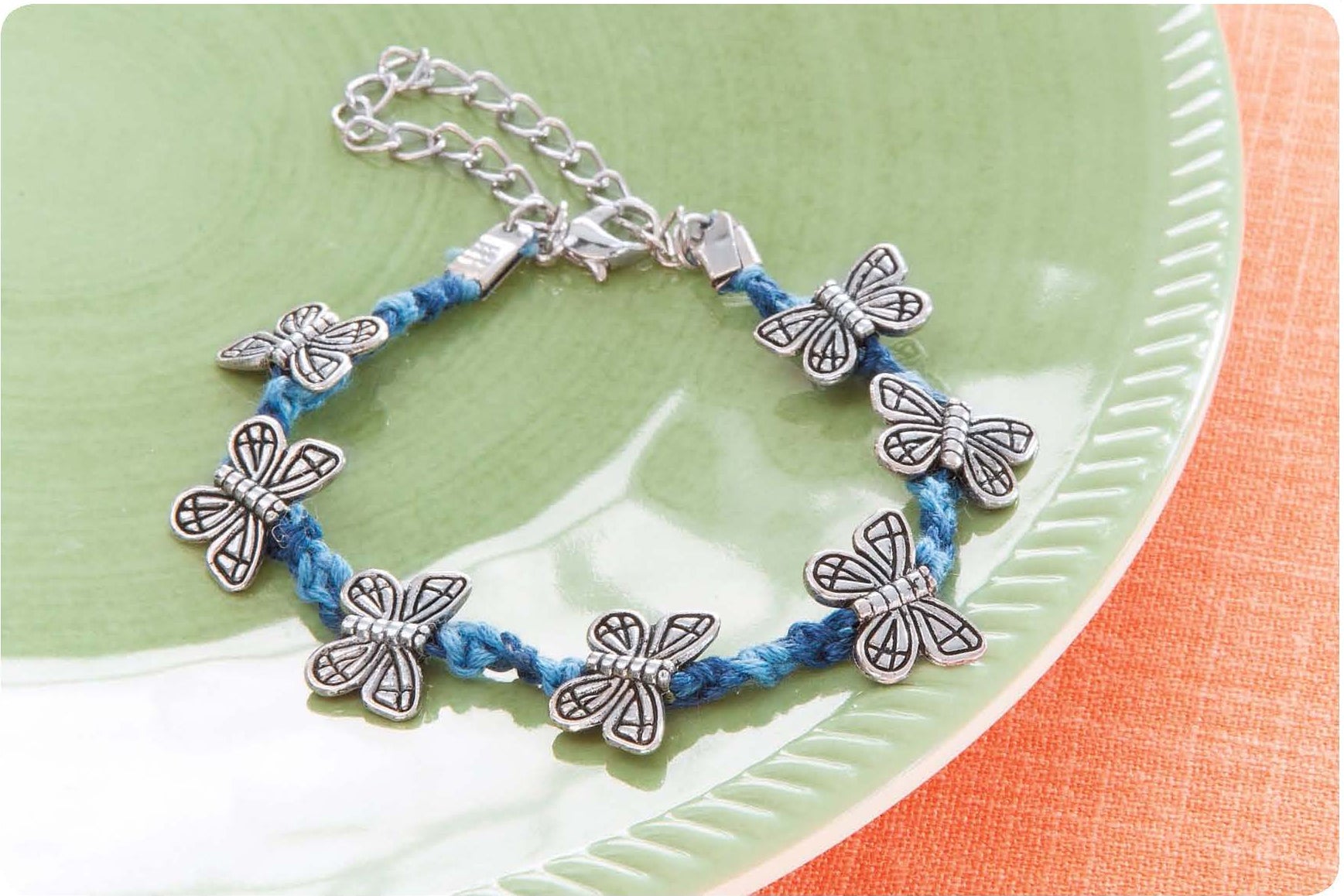 The "Friendship Bracelets Beyond the Basics Digital Download" by Leisure Arts features unique designs, such as a blue braided bracelet with six silver butterfly charms, perfect for creating standout pieces.