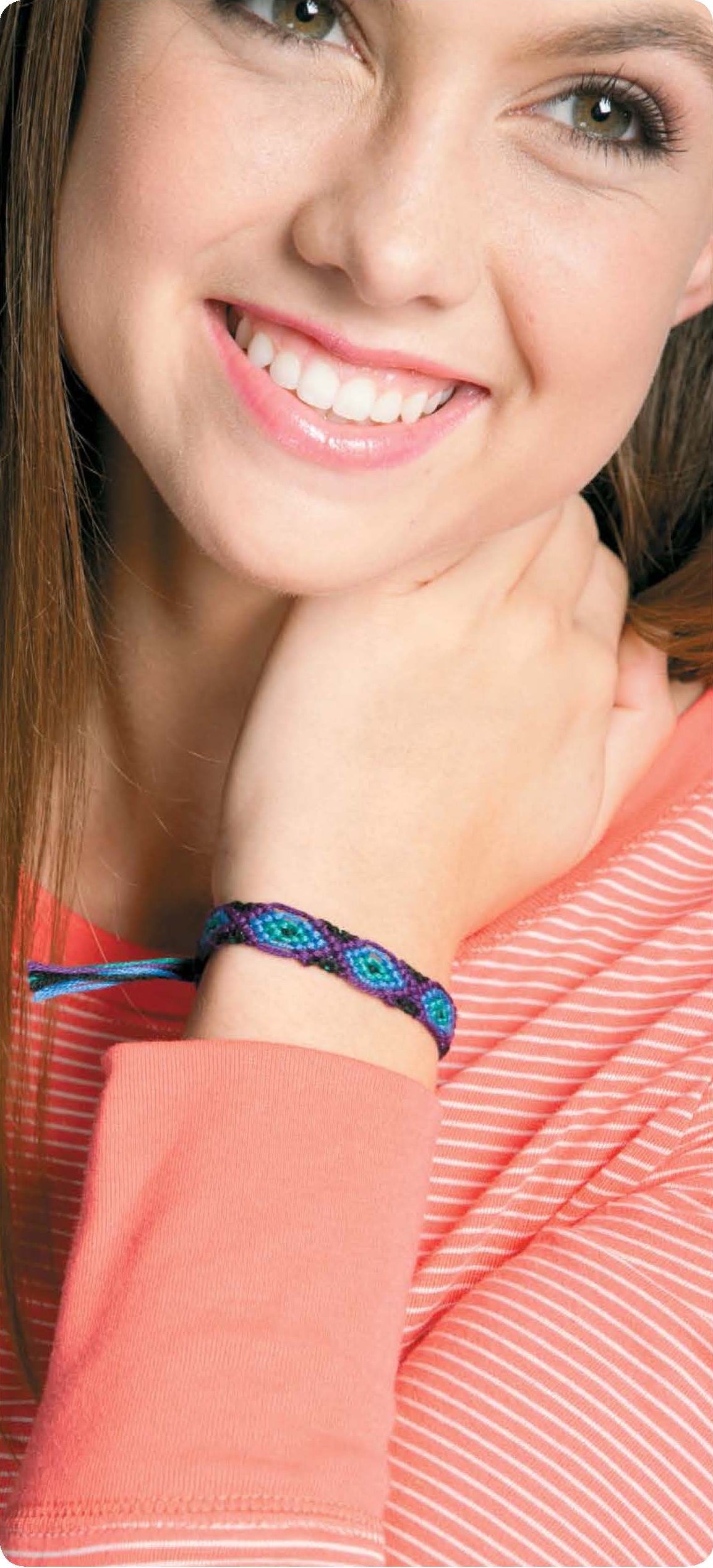 A smiling young woman wearing a coral and white striped top showcases a blue and purple bracelet, inspired by unique designs from the Leisure Arts "Friendship Bracelets Beyond the Basics" digital download.