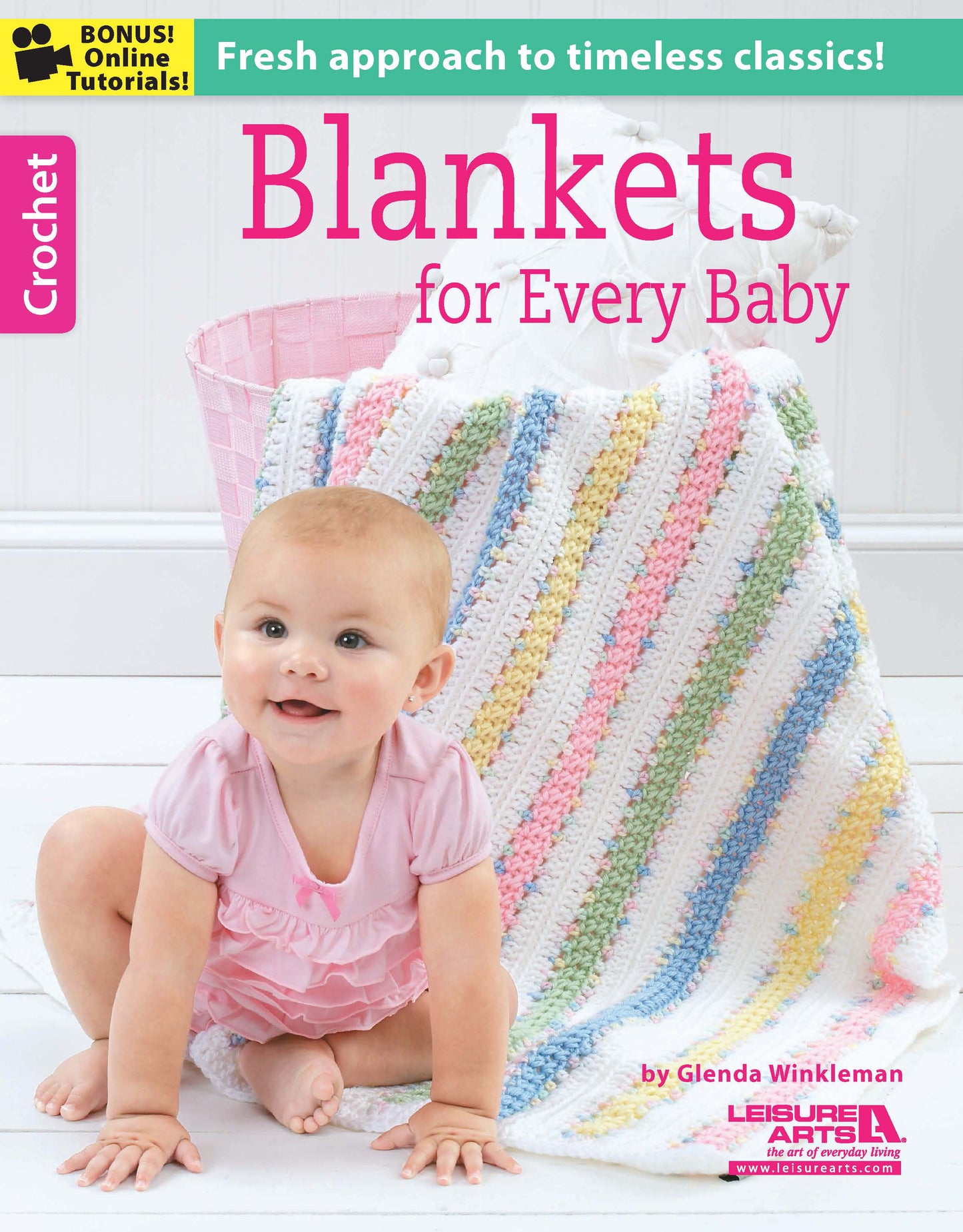 A smiling baby in pink sits on a white surface before a pastel crochet blanket. The book "Crochet Blankets for Every Baby" by Leisure Arts offers beginner patterns with soft worsted yarn and includes online tutorials.