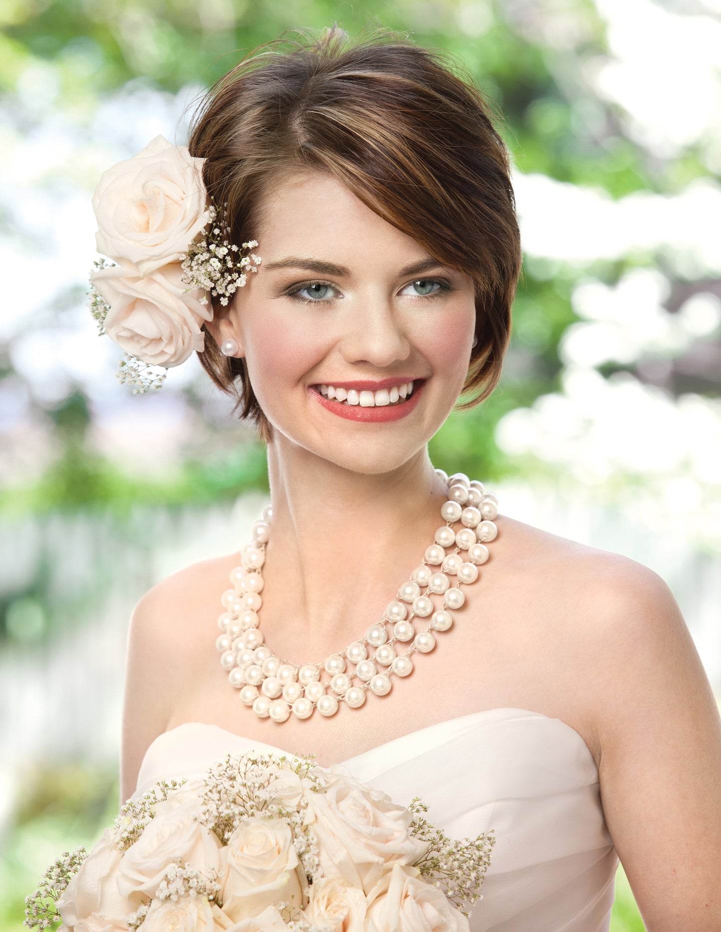 A smiling bride with short brown hair and cream roses wears a strapless gown and the beaded "Formal Jewelry—Crochet With Beads for Extra-Easy Glamour!" by Leisure Arts; she holds white roses, outdoors amid green foliage.