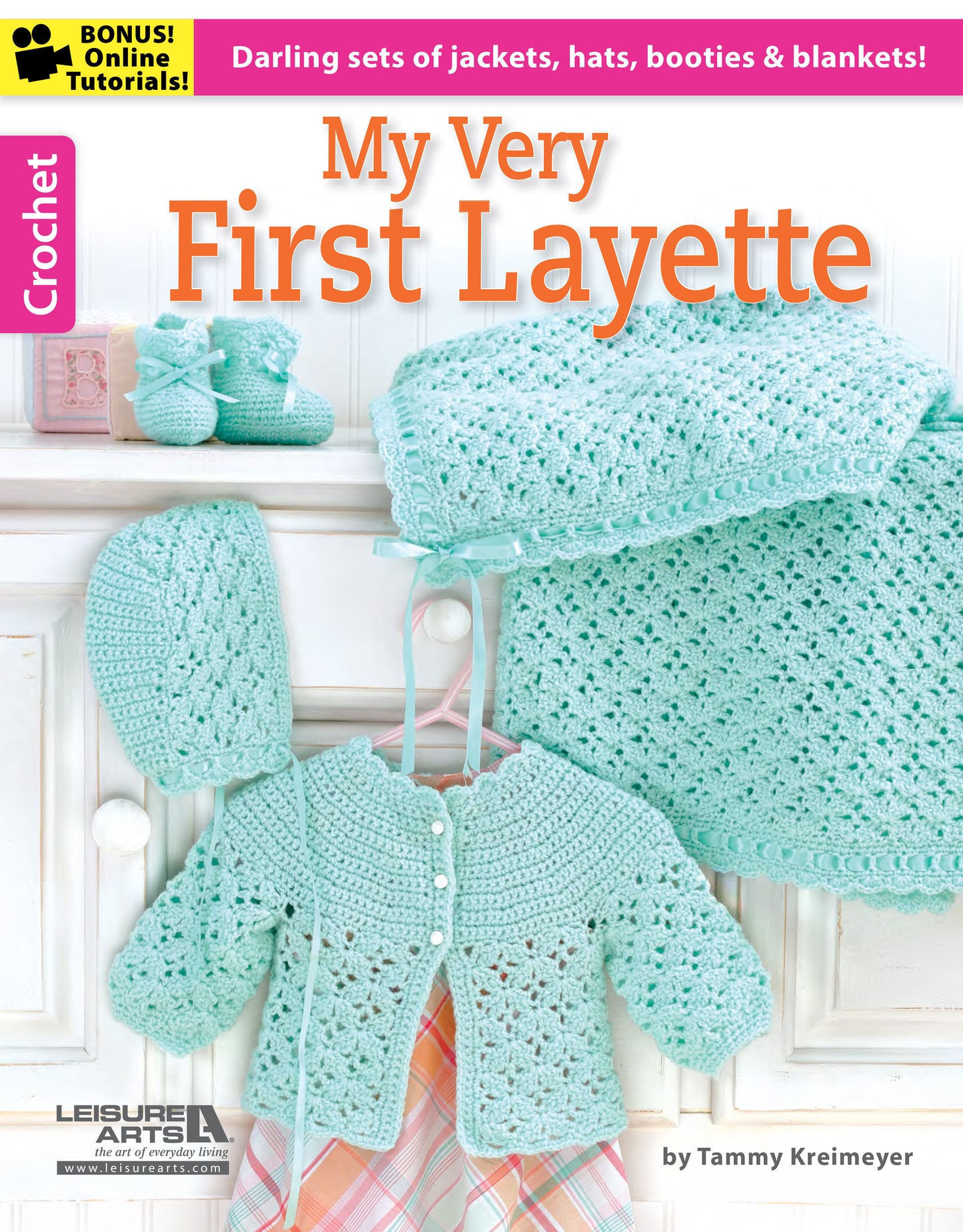The cover of "My Very First Layette 2" by Leisure Arts displays pastel green crochet baby items—bonnet, sweater, booties, and blanket—highlighting simple projects for cute baby sets. Includes online tutorial info and a soft pastel design.