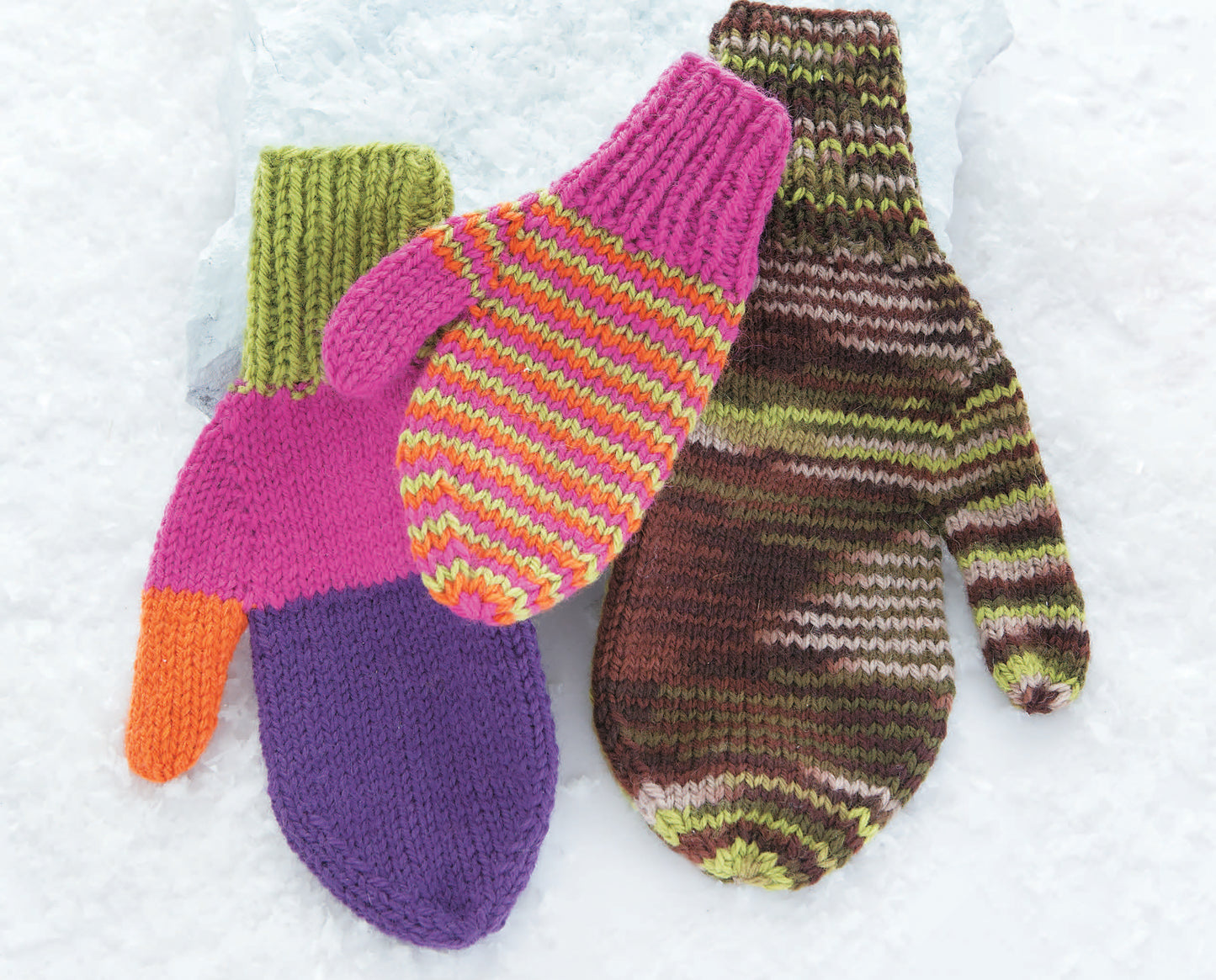 Three colorful mittens from Leisure Arts' "10-20-30 Minutes to Learn to Knit" are shown on snow: one is purple, pink, orange, and green; another is striped pink/yellow with a green cuff; the third features brown, green, and cream tones.