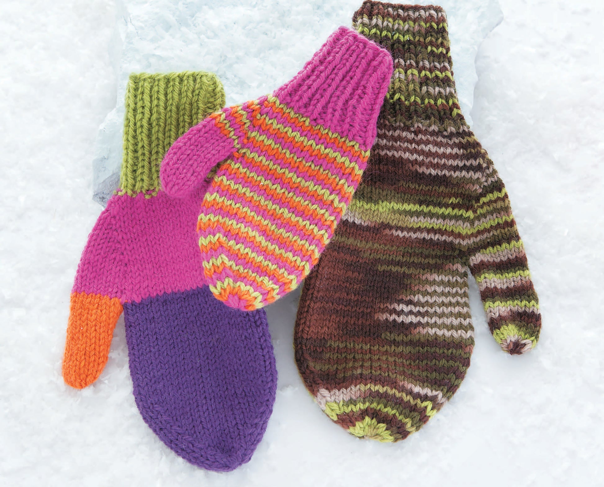Three colorful mittens from Leisure Arts' "10-20-30 Minutes to Learn to Knit" are shown on snow: one is purple, pink, orange, and green; another is striped pink/yellow with a green cuff; the third features brown, green, and cream tones.