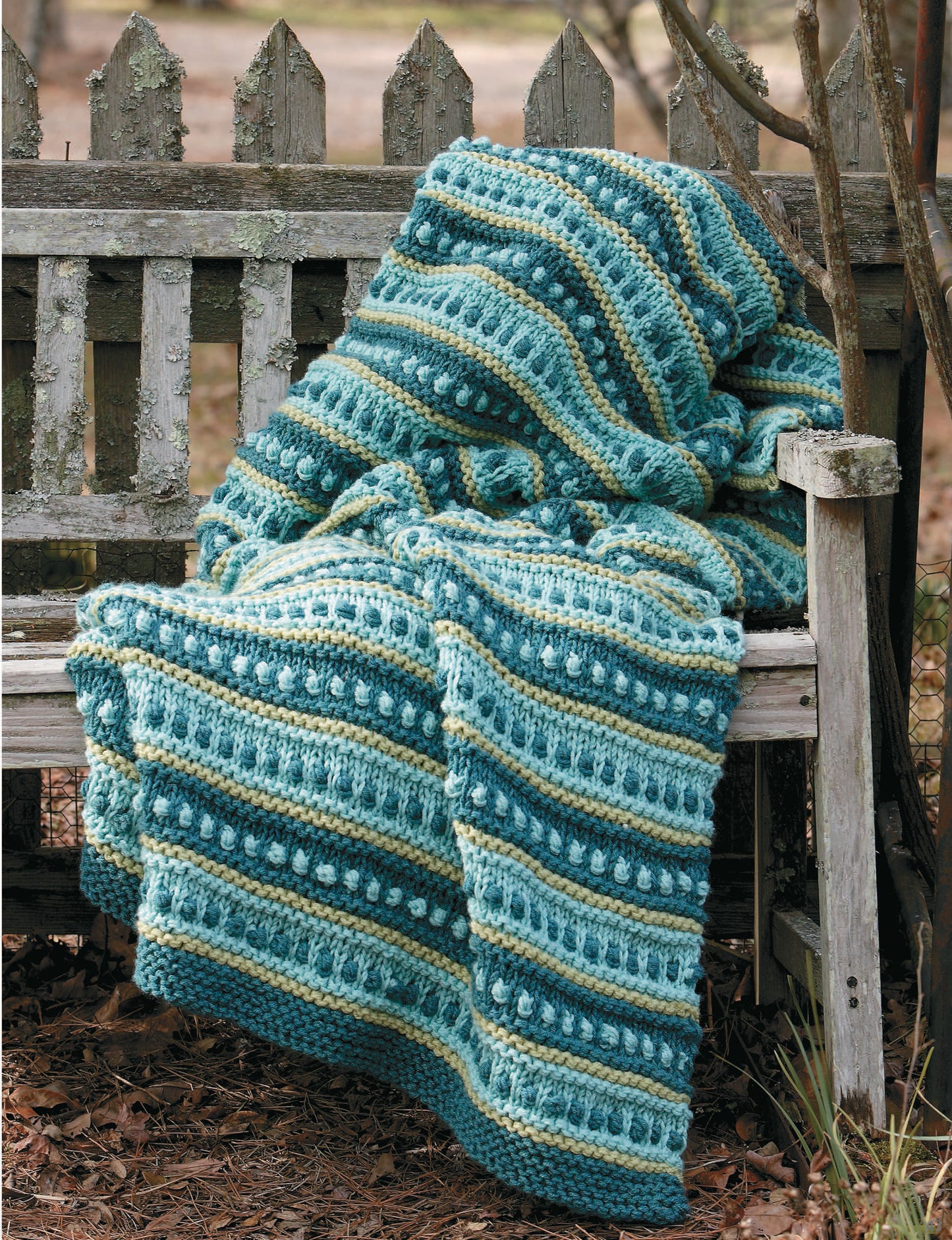 A textured, striped crocheted blanket in blue, green, and cream inspires your next project—try making your own with Leisure Arts’ “10-20-30 Minutes to Learn to Knit” digital download for easy beginner instructions.