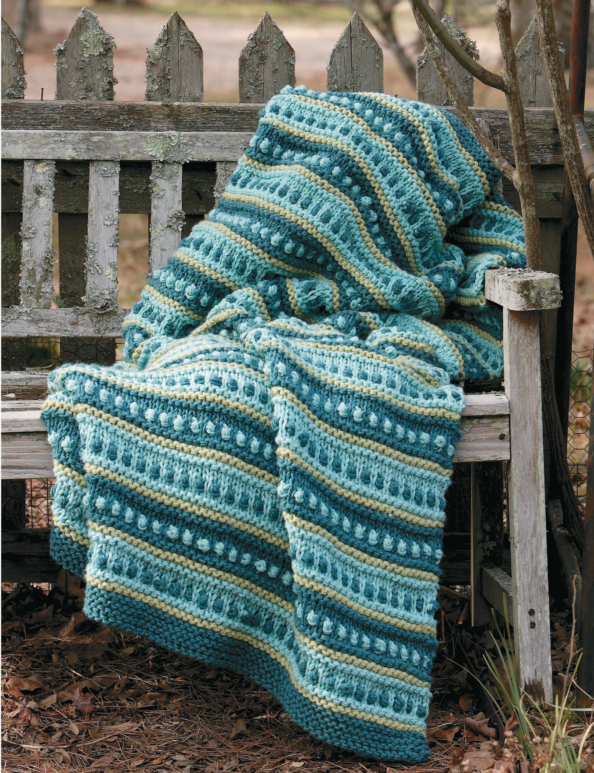 A textured, striped crocheted blanket in blue, green, and cream inspires your next project—try making your own with Leisure Arts’ “10-20-30 Minutes to Learn to Knit” digital download for easy beginner instructions.