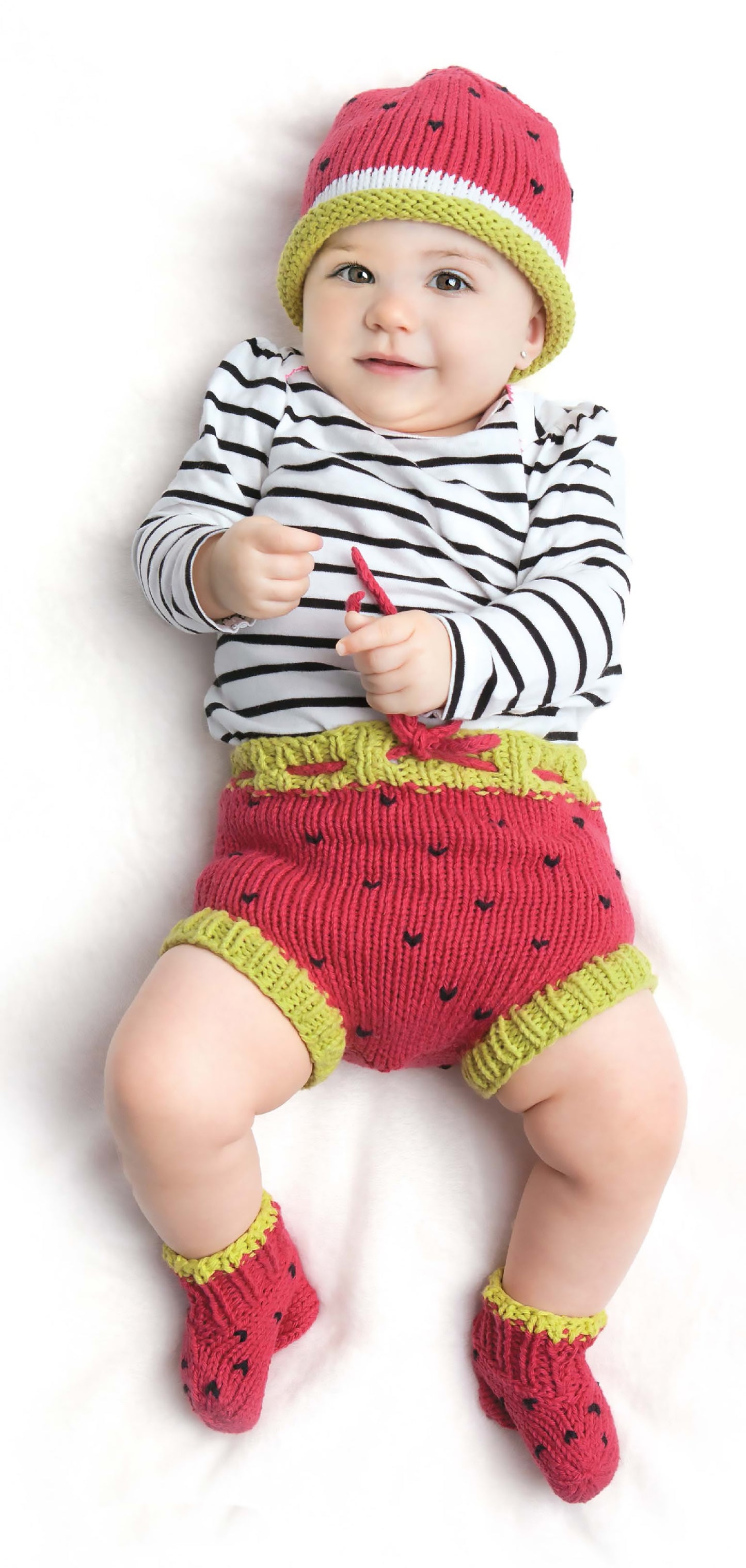 A baby models Leisure Arts' Diaper Cover Sets—Fun Outfits for Baby Photos & Playtime!—wearing a striped long-sleeve shirt, knit hat, watermelon shorts and socks, plus a matching diaper cover. Bonus! Online Tutorials included.