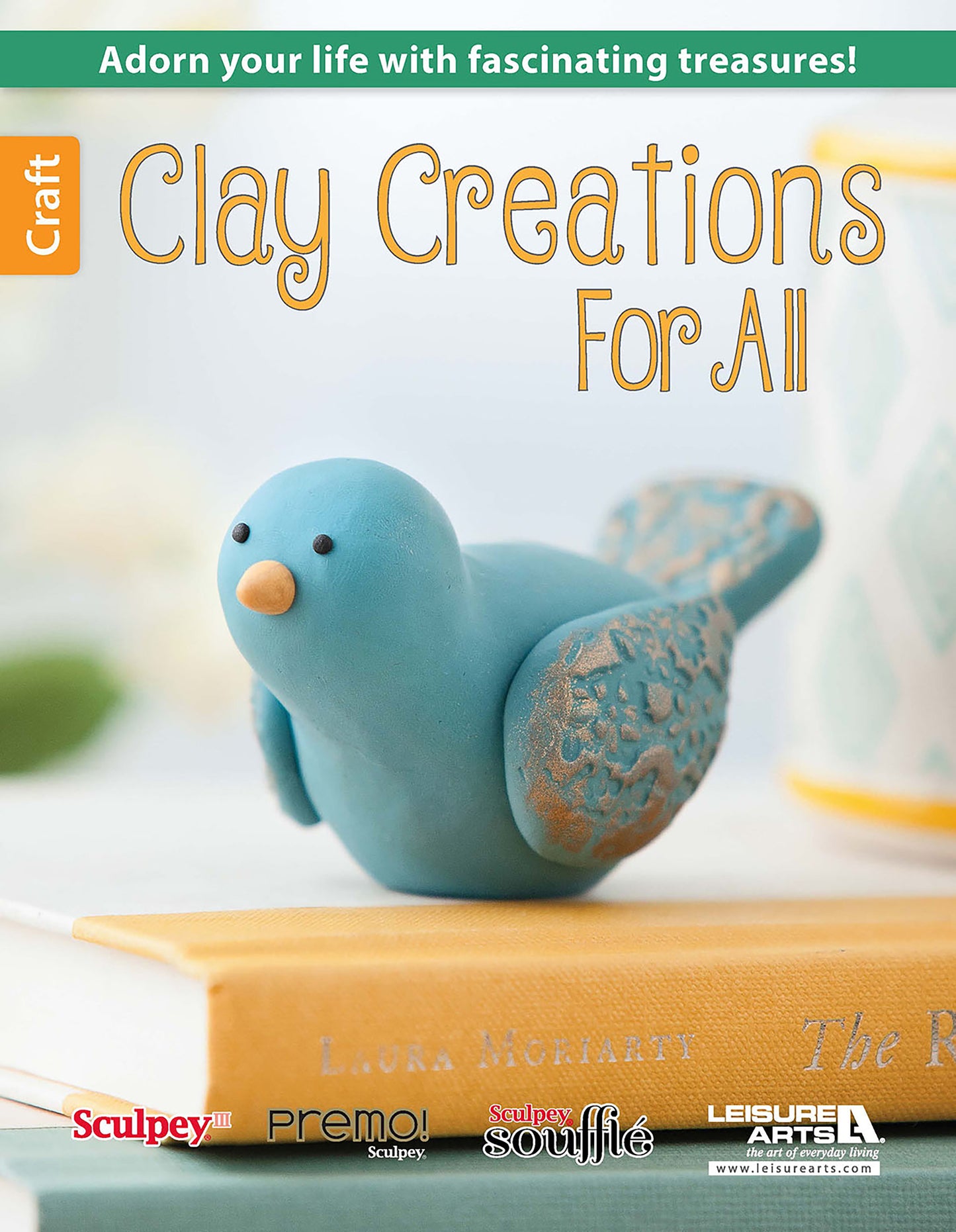 A blue polymer clay bird with gold accents rests on books. The text says: Adorn your life with fascinating treasures! Beginner projects—Clay Creations for All by Leisure Arts. Craft and brand logos appear below.