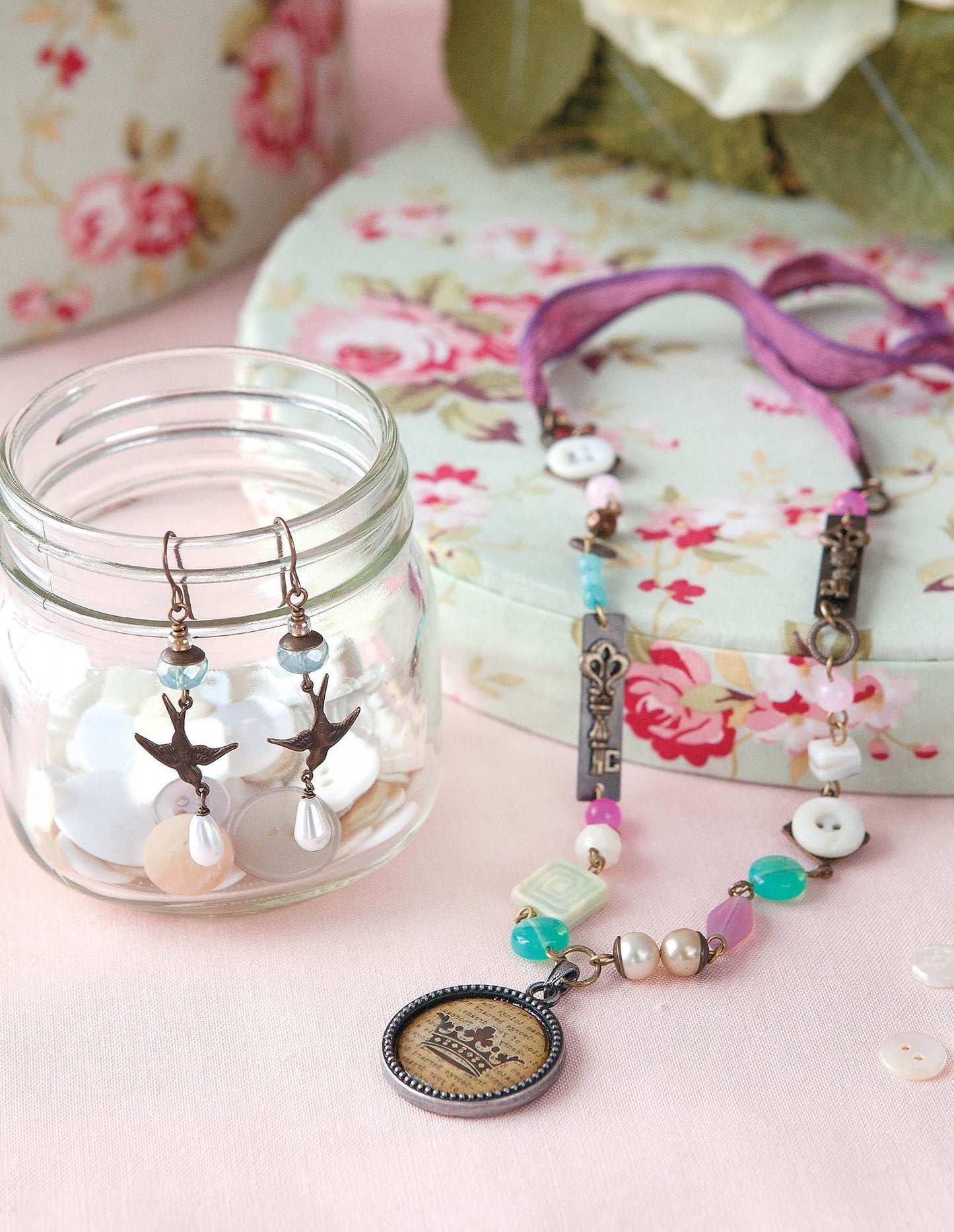 Easy Vintage Jewelry by Leisure Arts features bird-shaped earrings on a glass jar and a colorful beaded necklace next to a floral box—ideal for anyone interested in beginner jewelry projects or vintage crafts.