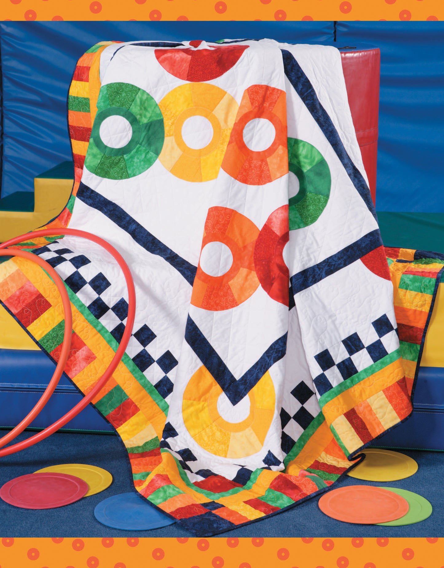The Leisure Arts "Fun Colorful Quilts" digital download showcases bold quilting patterns with green, orange, red, and yellow rings plus black-and-white checkered borders—perfect for bright kids' play areas or draping over a red chair.