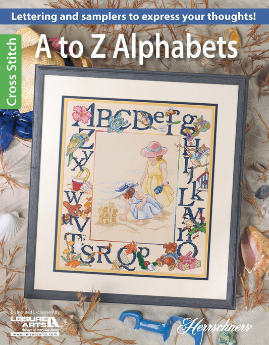 The "A to Z Alphabets Cross Stitch" by Leisure Arts features a framed sampler with floral accents, alphabet letters, and two girls in hats playing with a dog on the beach—perfect as a charming cross-stitch book cover.