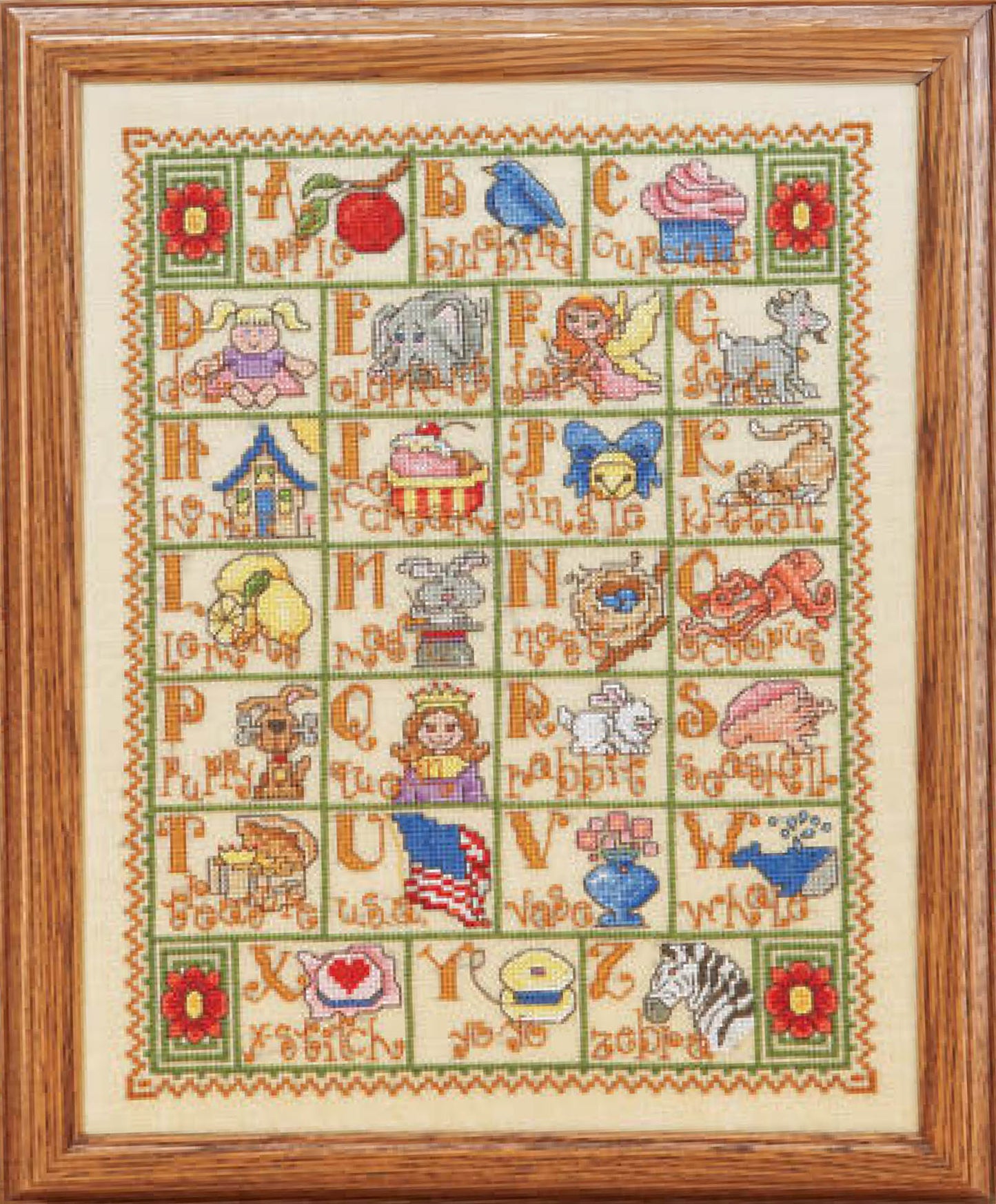 The Leisure Arts A to Z Alphabets Cross Stitch features framed alphabet lettering, each letter with a vibrant object or animal, and is finished with a green and red floral border.