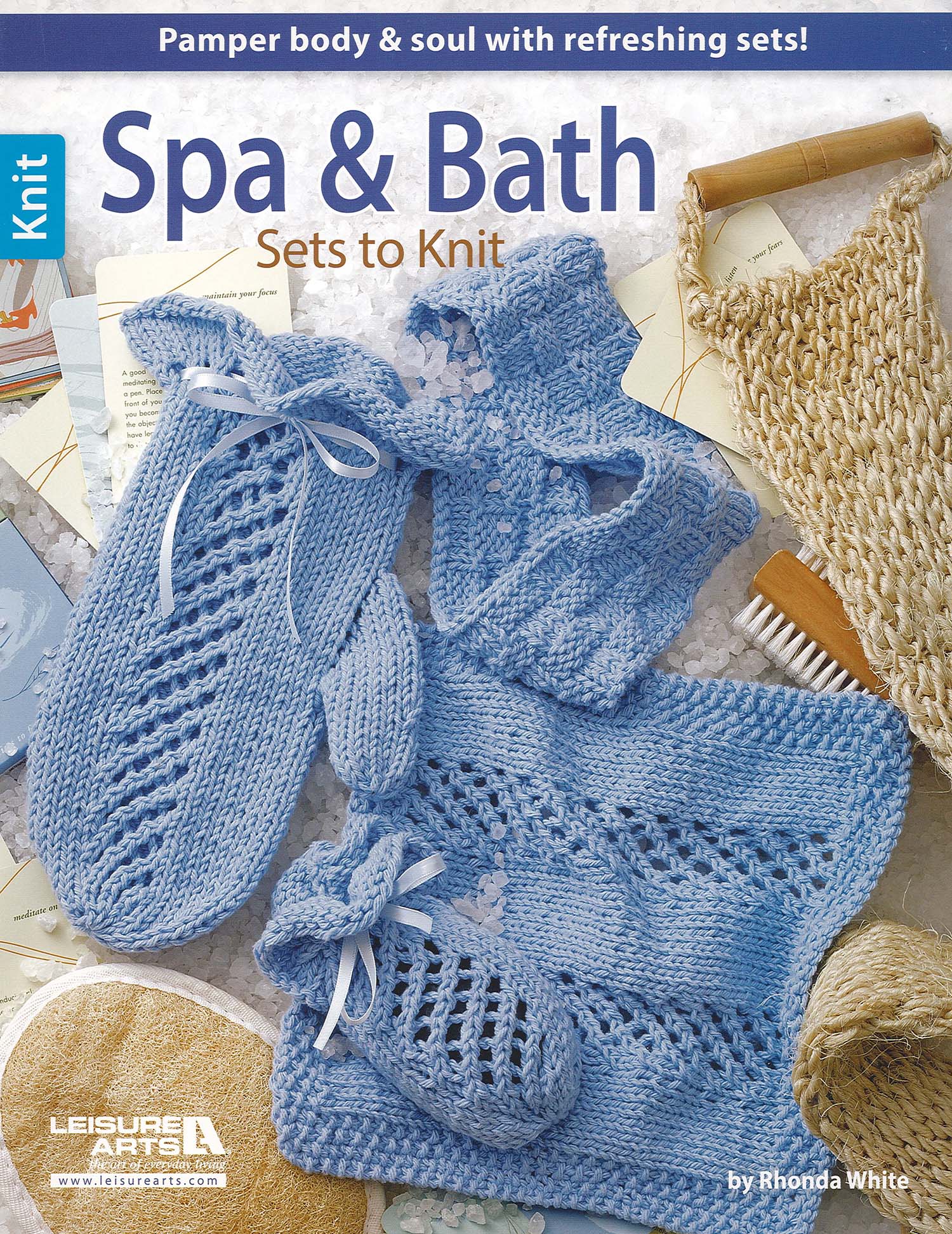 Cover of Leisure Arts’ "Spa & Bath Sets to Knit Digital Download," featuring blue hand-knitted bath accessories—slippers, washcloths, a scrubby, and mitt—displayed on a bath mat with soap, candle, and bath products.