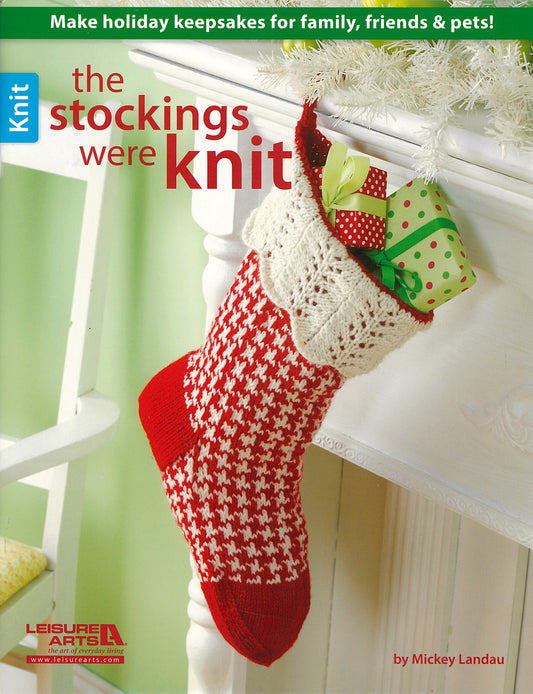 A Christmas stocking filled with gifts hangs on a mantel beside the magazine "The Stockings Were Knit" by Leisure Arts, featuring ideas for making holiday keepsakes for family, friends, and pets.