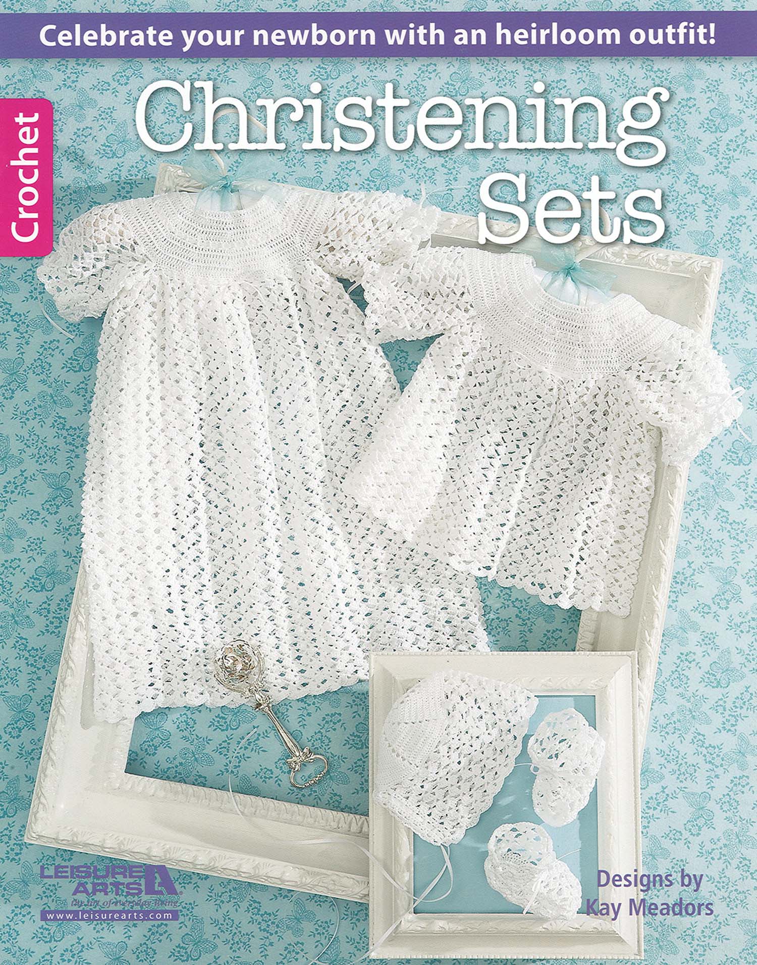 Cover of “Christening Sets—Celebrate Your Newborn With an Heirloom Outfit!” by Leisure Arts shows two lacy white baby dresses, bonnet, and booties in white frames on blue. Features timeless crochet christening outfit patterns for newborns.