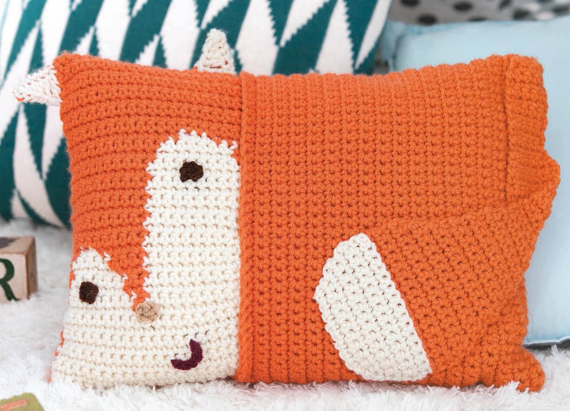 The Leisure Arts Kids Animal Pillows feature an orange fox design with cream accents and black stitched eyes, making it a cute decorative accessory for children’s rooms alongside other pillows and toys.