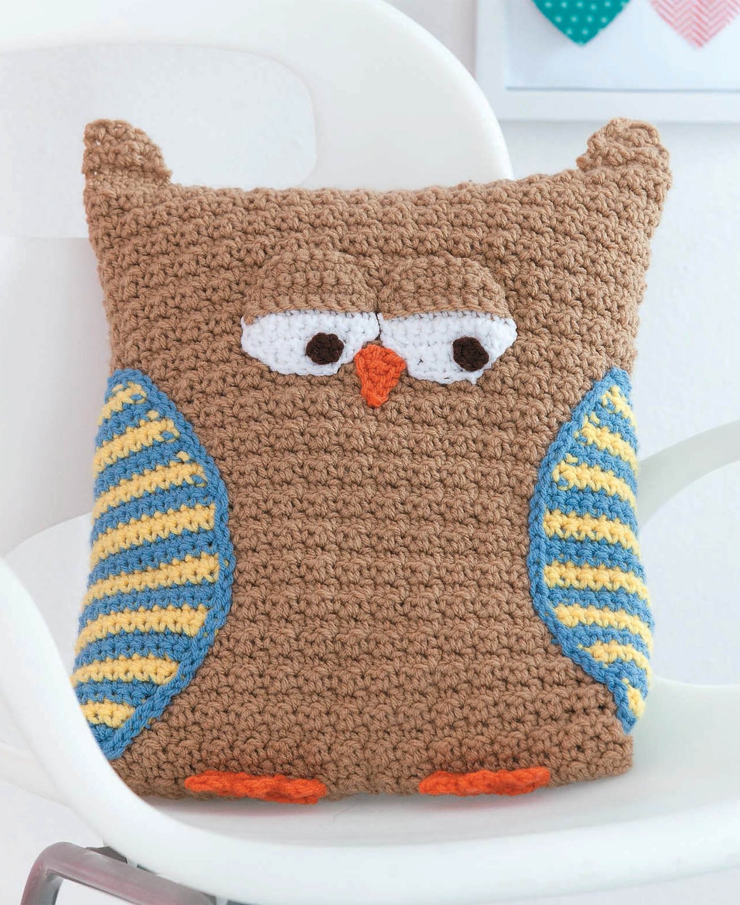 The Leisure Arts Kids Animal Pillows collection features a crocheted owl pillow with brown yarn, white eyes, an orange beak and feet, plus blue and yellow striped wings—a charming decorative accent for children who love animal pillows.