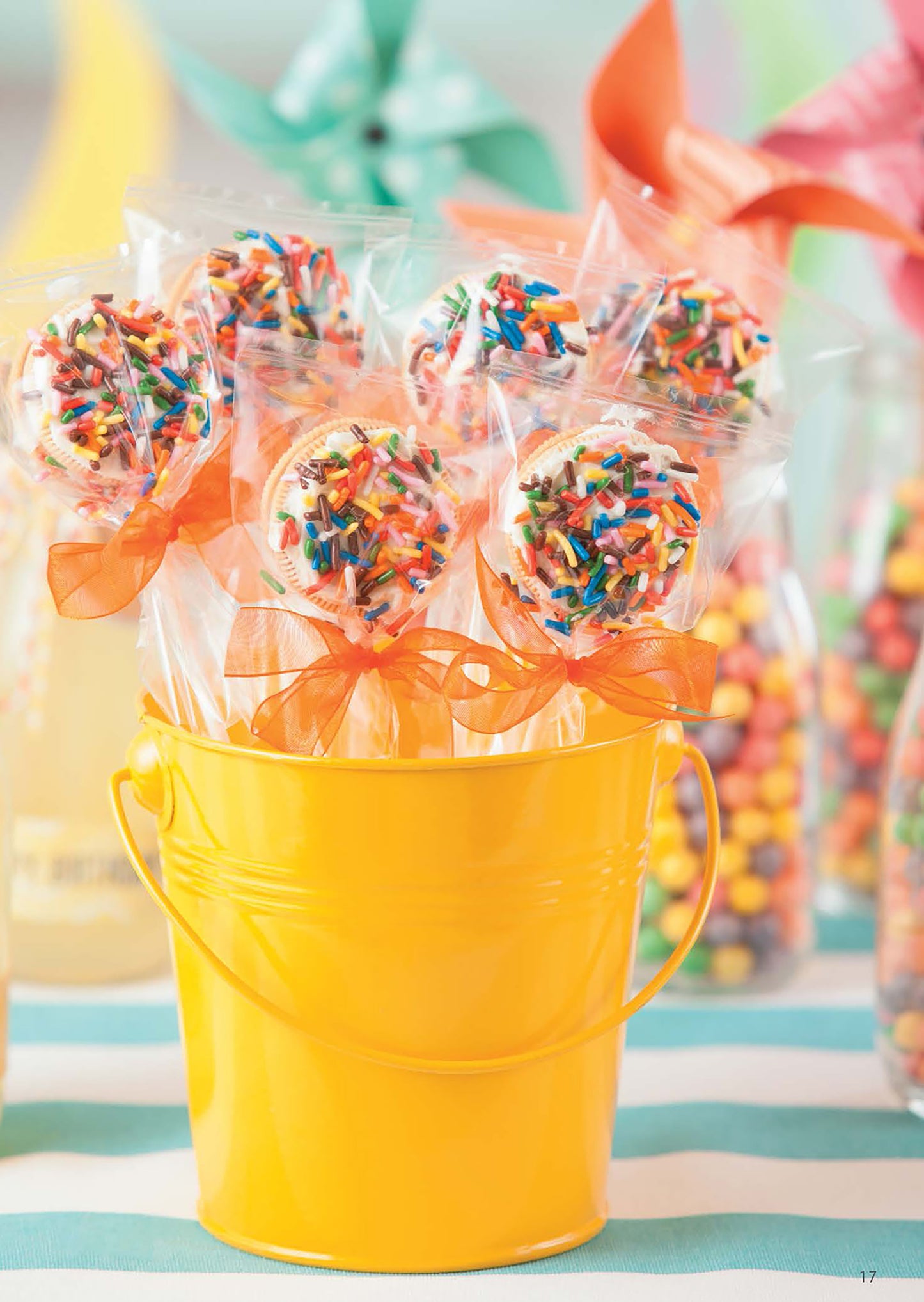 The "Celebrate Birthdays" kit by Leisure Arts offers unique DIY party crafts for kids or adults, featuring a yellow bucket filled with sprinkle-covered, individually wrapped cake pops tied with orange ribbons—ideal for festive gatherings.