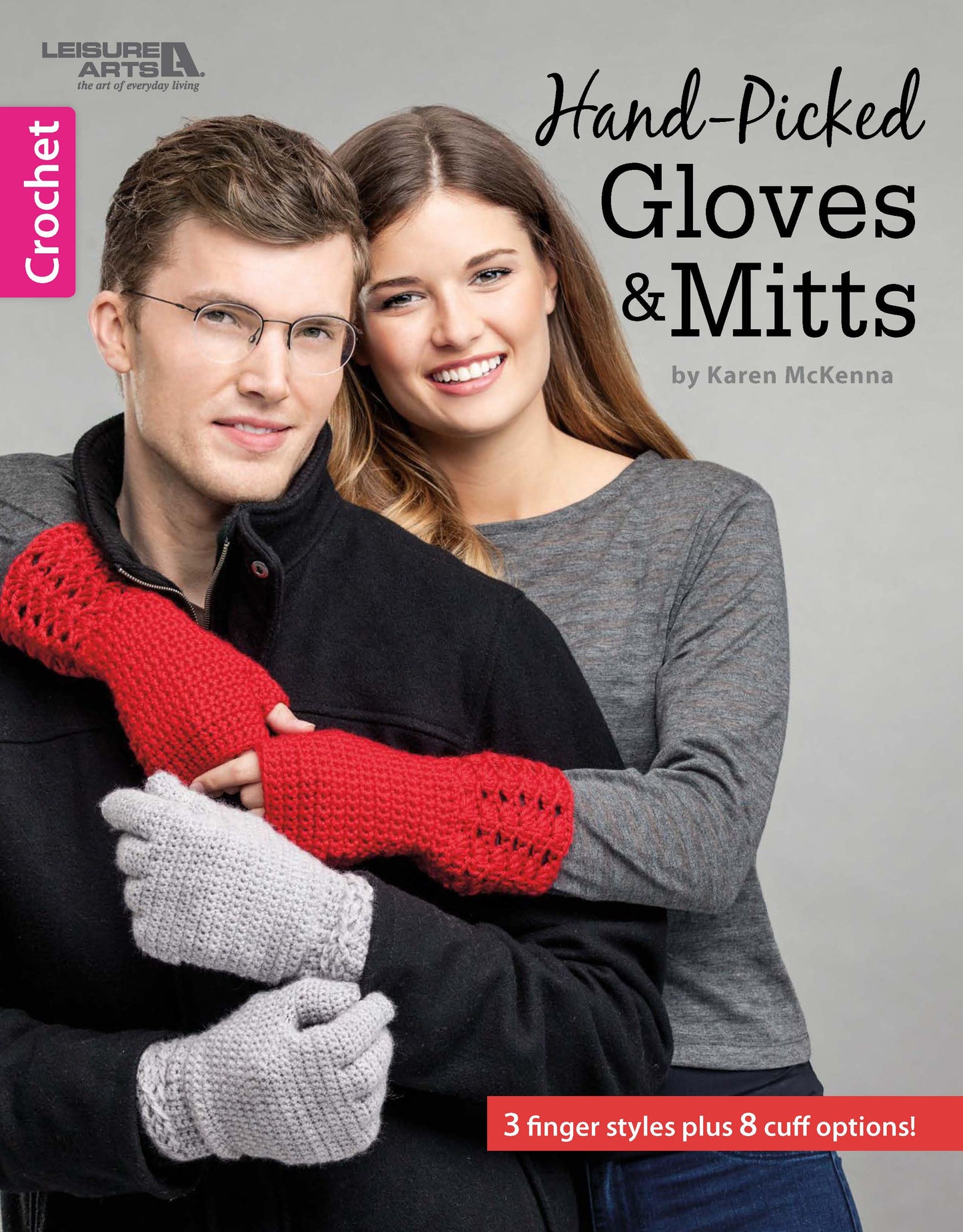 A smiling woman in a gray shirt hugs a man from behind; she wears red crochet mittens and he wears gray crochet gloves. This image appears on the cover of "Hand-Picked Gloves & Mitts" by Leisure Arts.