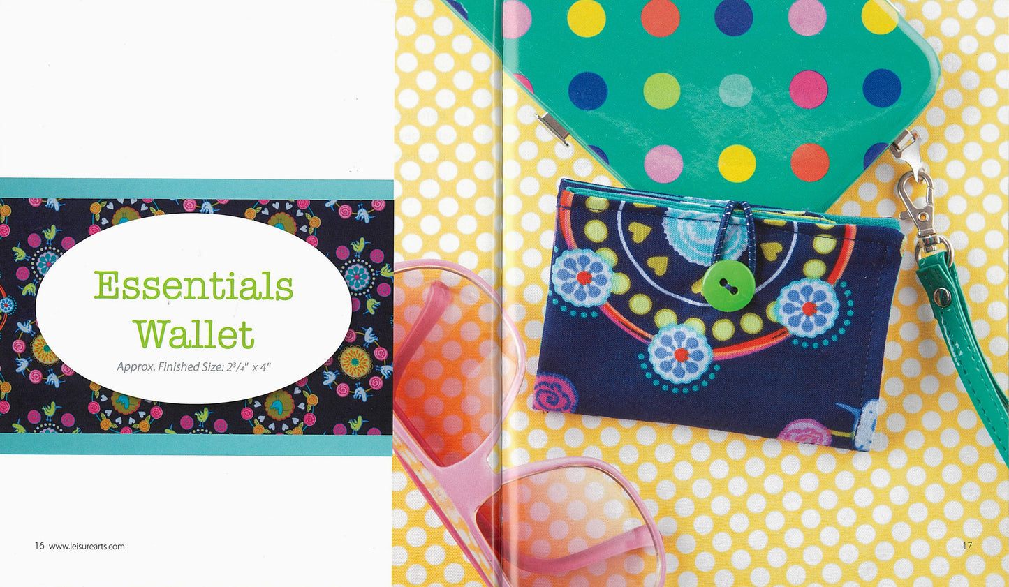 The Simple Sewing essentials wallet by Leisure Arts, ideal for beginner sewing and made with vibrant fabrics, rests on a yellow polka dot surface beside a green polka dot clutch and pink sunglasses. Text reads: “Approx. Finished Size: 2½ x 4”.