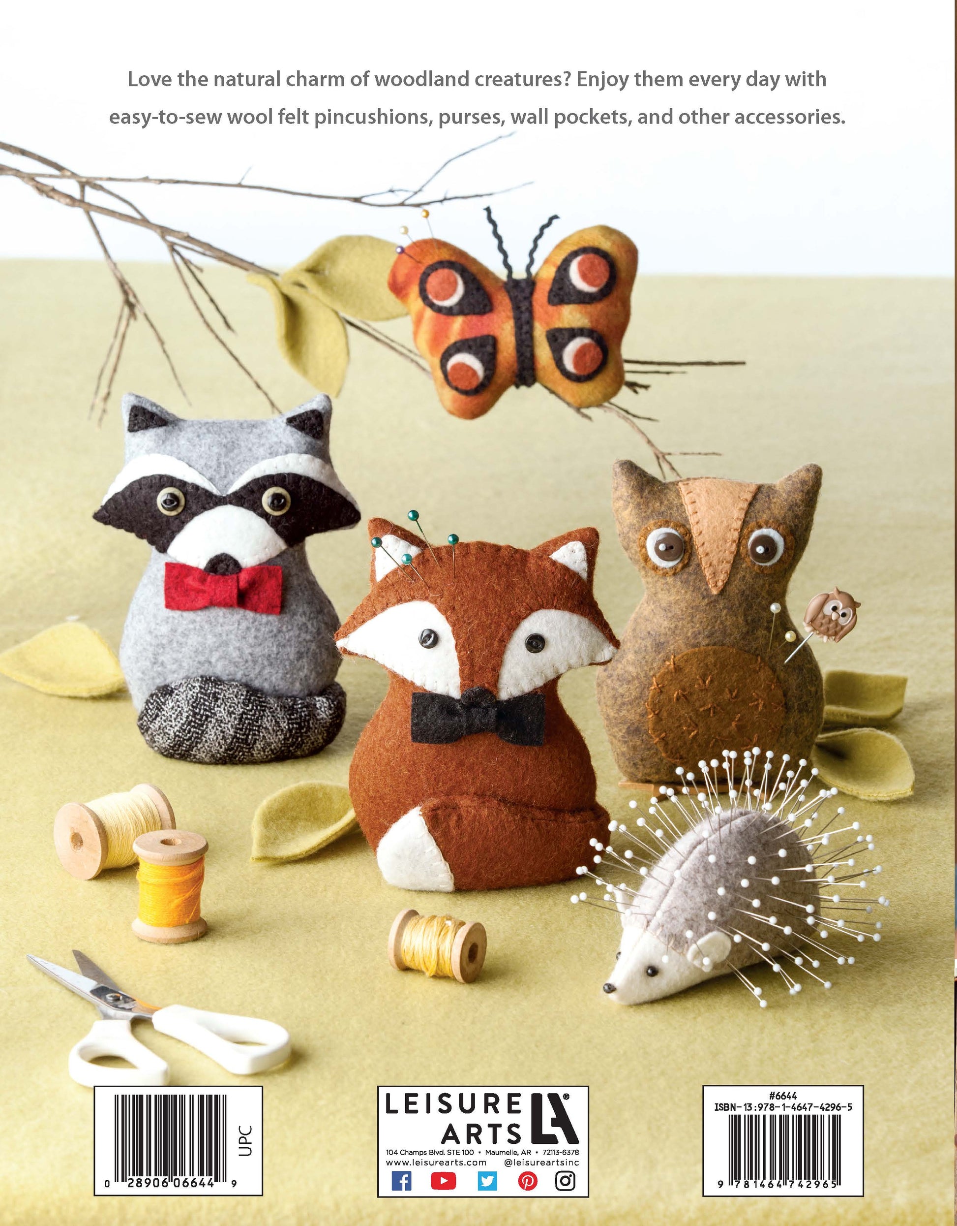Four easy-to-sew felt critters—a raccoon, butterfly, owl, fox—and a wool felt hedgehog pincushion from Leisure Arts' "Felt Crafty Critters Digital Download" sit on green felt with sewing supplies; guides and publisher info frame the scene.