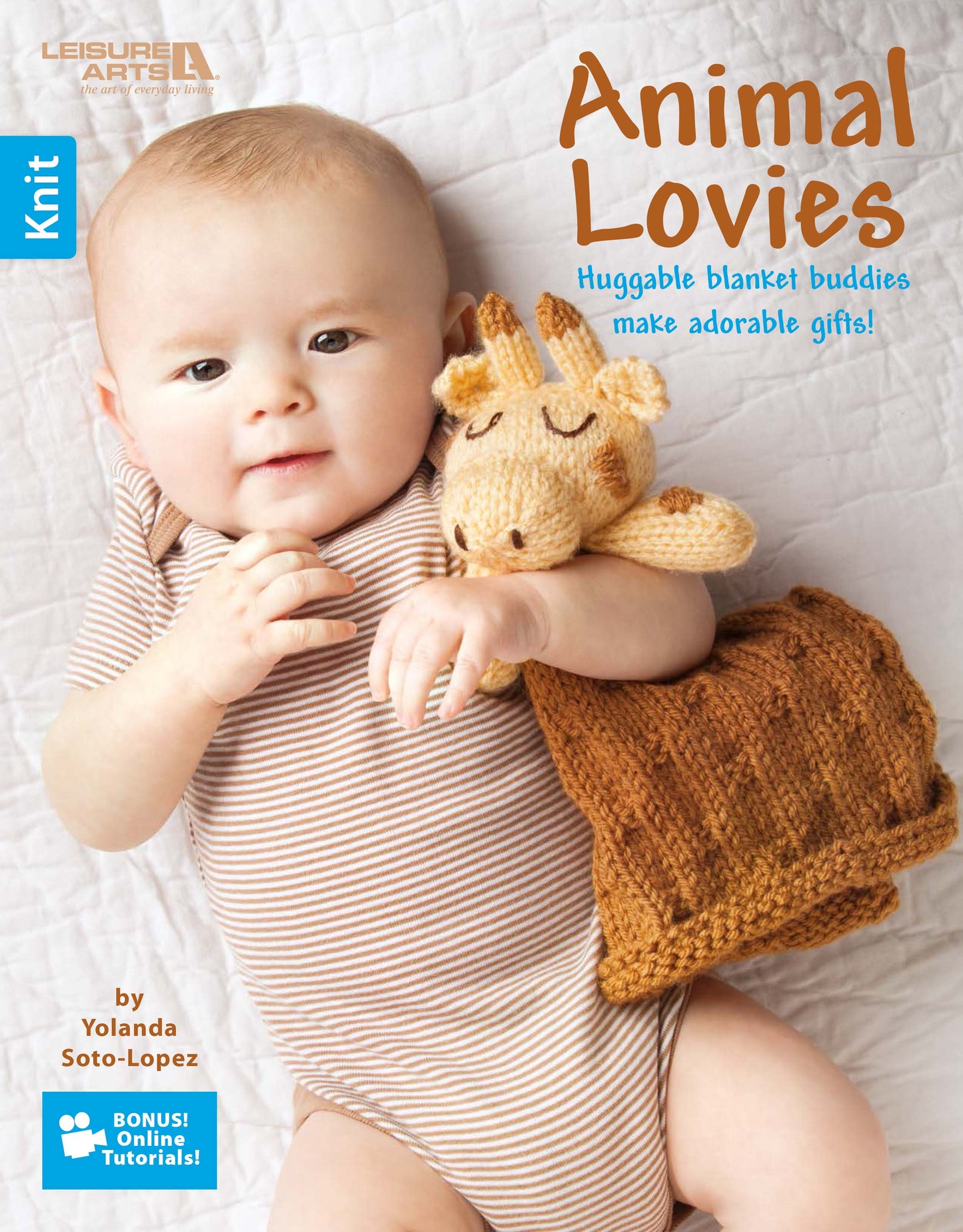 A baby in a striped onesie lies on a soft white surface, holding a knit giraffe lovie. The book shown is Animal Lovies—Huggable Blanket Buddies Make Adorable Gifts! Bonus! Online Tutorials! by Leisure Arts.