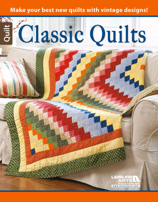 A patchwork quilt with a geometric stair-step pattern in red, yellow, blue, and green drapes over a beige sofa on the cover of Classic Quilts by Leisure Arts.