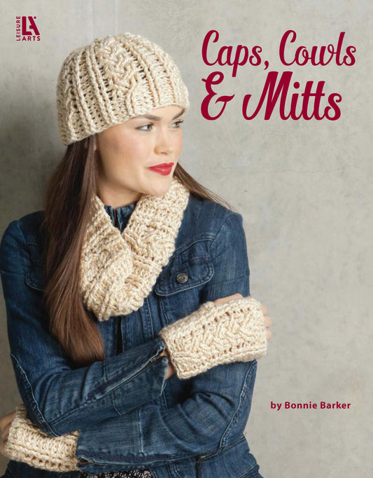 A woman in a blue denim jacket models a cream cabled hat, cowl, and fingerless mitts. The image text reads Crochet Caps, Cowls & Mitts by Leisure Arts.