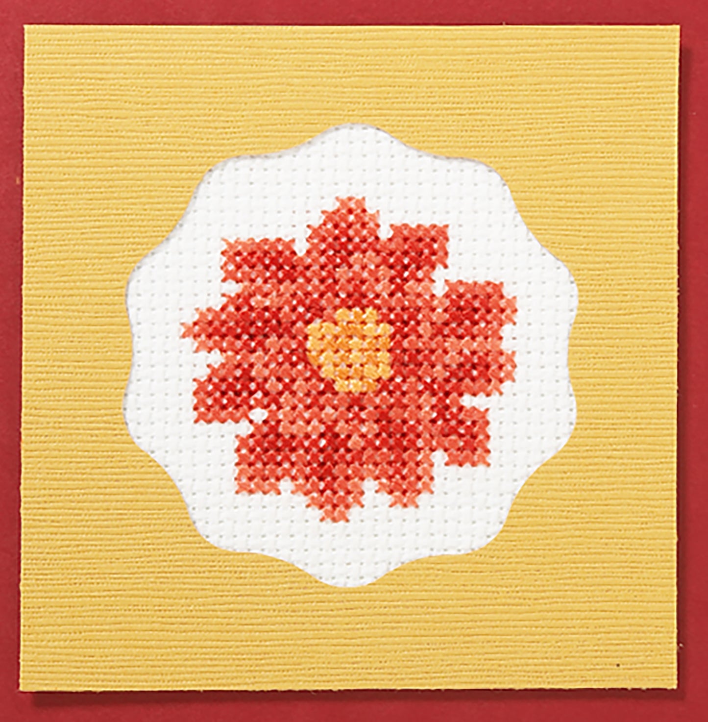 The Fabulous Florals Cross Stitch Digital Download by Leisure Arts features a red and orange flower with a yellow center on white fabric, framed by scallops and set on a yellow square background with a red border.