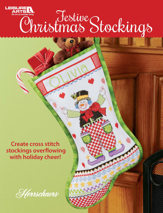 The Leisure Arts Festive Christmas Stockings hang on a door, featuring cross-stitched snowmen, vibrant patterns, “Olivia” personalization, and are filled with gifts like teddy bears—perfect for charming Christmas décor.