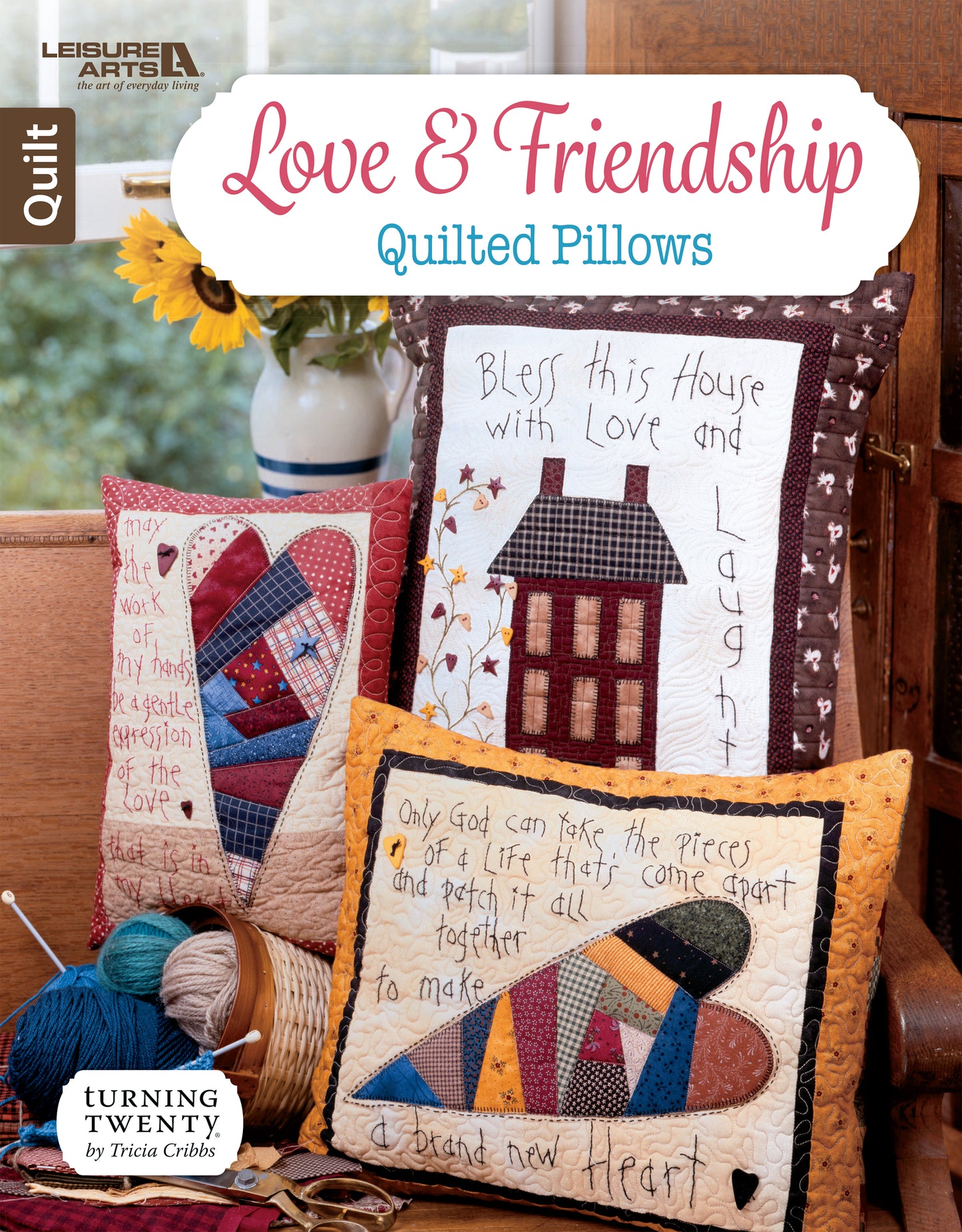 Three vibrant quilted pillows from Leisure Arts' Love & Friendship Quilted Pillows line feature embroidered designs and heartfelt messages, shown on a wooden bench with charming decor, sunflowers, and artistic free-motion quilting in the background.