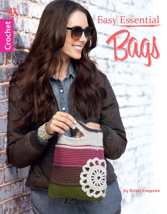 A smiling woman in sunglasses and a brown jacket holds a striped crocheted bag. Text: Easy Essential Bags Crochet by Leisure Arts—ideal for beginners wanting to create stylish crochet bags.