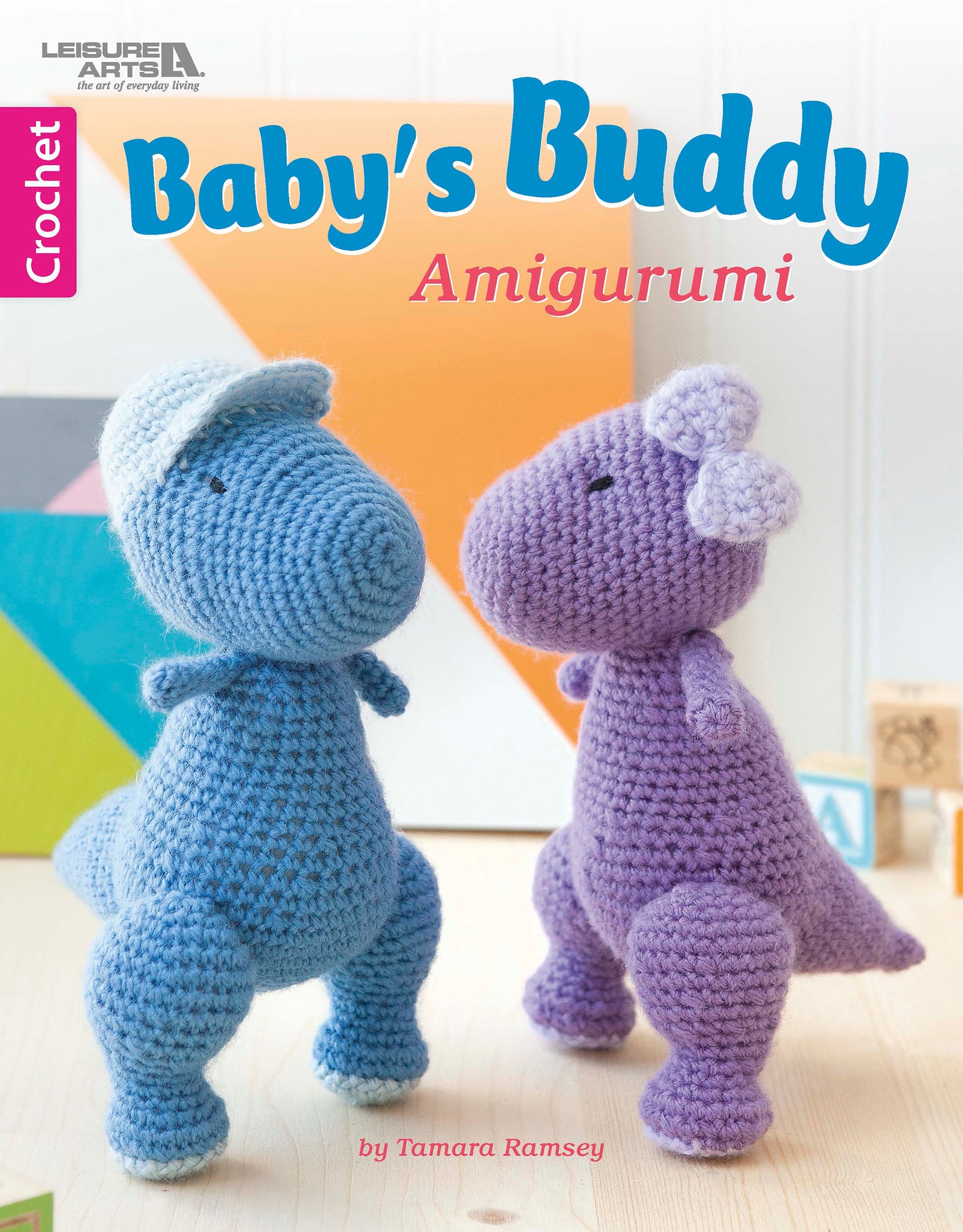 Cover of "Baby's Buddy Amigurumi" by Leisure Arts, featuring two cute crochet stuffed animals—a blue dinosaur with a cap and a purple one with a flower—on a light background. Great for beginner crochet baby toy patterns.