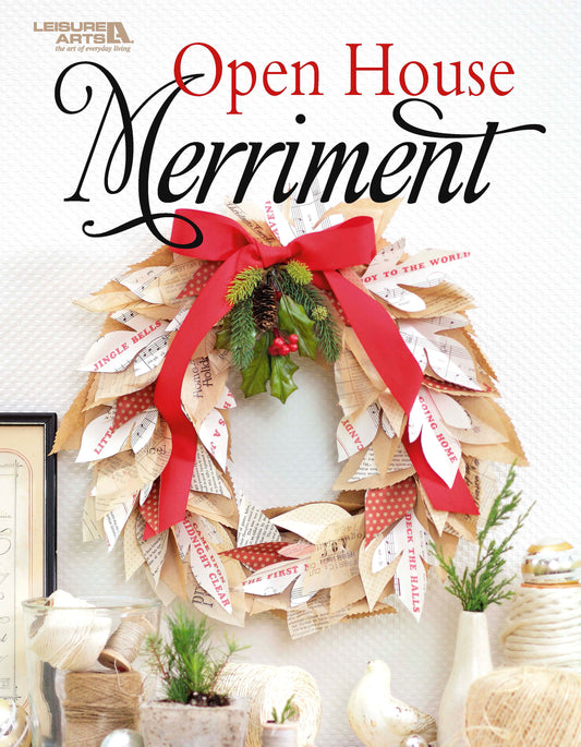 The Open House Merriment handmade holiday wreath by Leisure Arts is crafted from book pages, burlap, and a red ribbon, adorned with pine and berries. Hanging on a white wall with “Open House Merriment” above it, this wreath is perfect for adding festive accents to your seasonal decor.