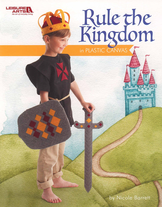 A young boy in a knight costume and kids’ crown holds a gray toy sword and shield, standing on a path with a colorful castle behind. Text: “Rule the Kingdom in Plastic Canvas by Nicole Barrett – Leisure Arts.”.