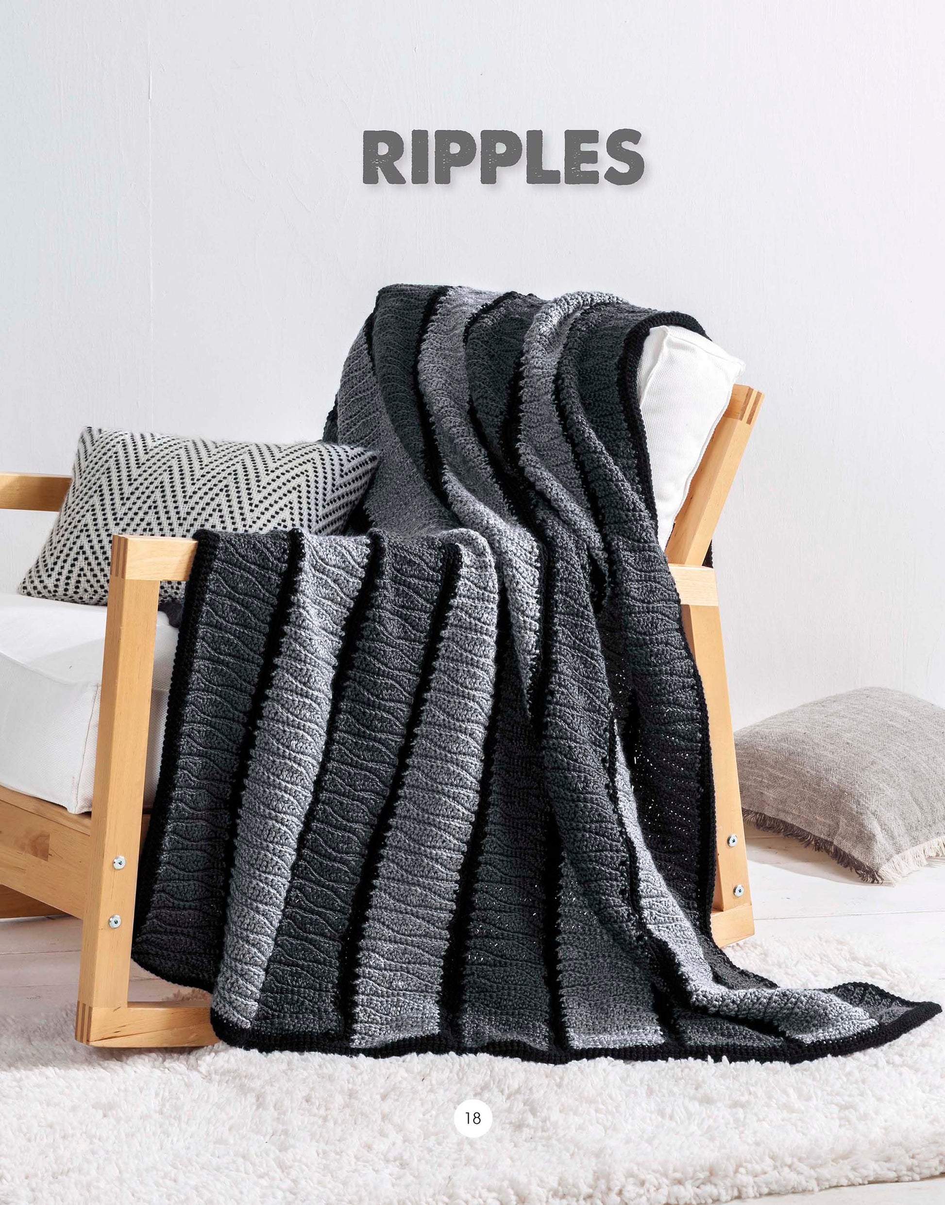 A Graphic Pattern Afghans crochet throw by Leisure Arts, in black and grey ripple stripes with geometric details, is draped over a wooden chair with decorative pillows on a white fluffy rug. Text reads RIPPLES.