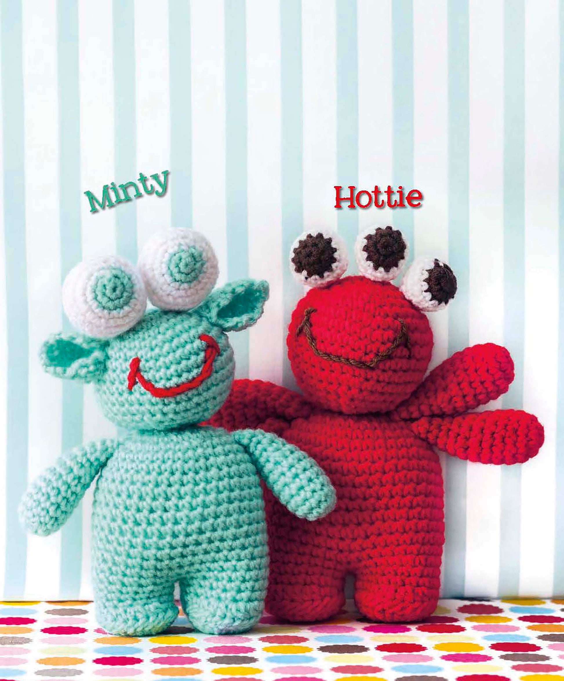 Two crocheted amigurumi monsters, “Minty” in aqua with three eyes and ears, and “Hottie” in red with wide arms, stand side by side. Download this Cute Amigurumi Monsters pattern by Leisure Arts to create your own unique plush toys!.