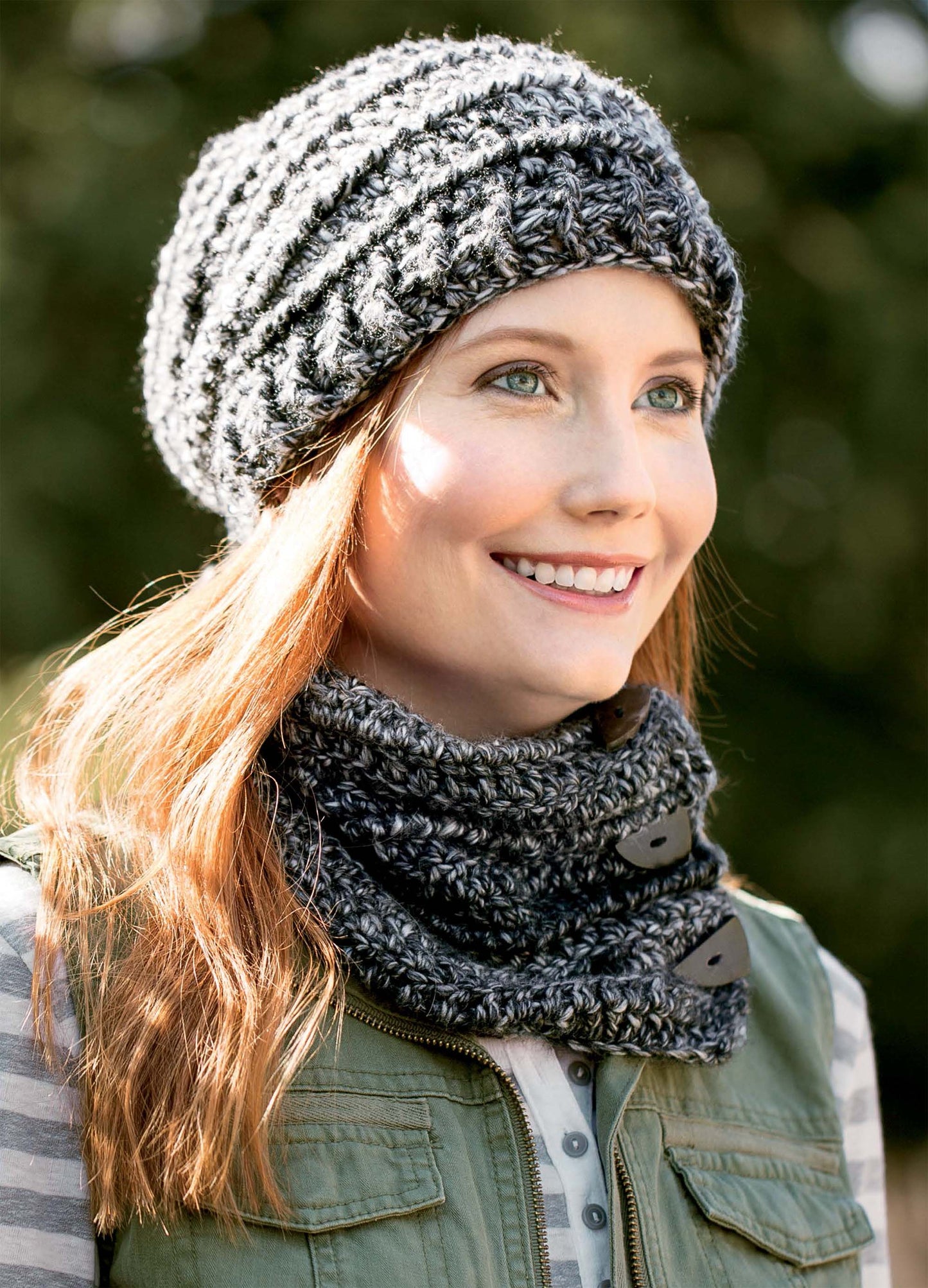 Smiling woman outdoors wears a chunky knit gray hat and matching button cowl—just like the cozy patterns in the Textured Hats, Scarves, & Cowls Digital Download by Leisure Arts, perfect for beginner crochet projects.