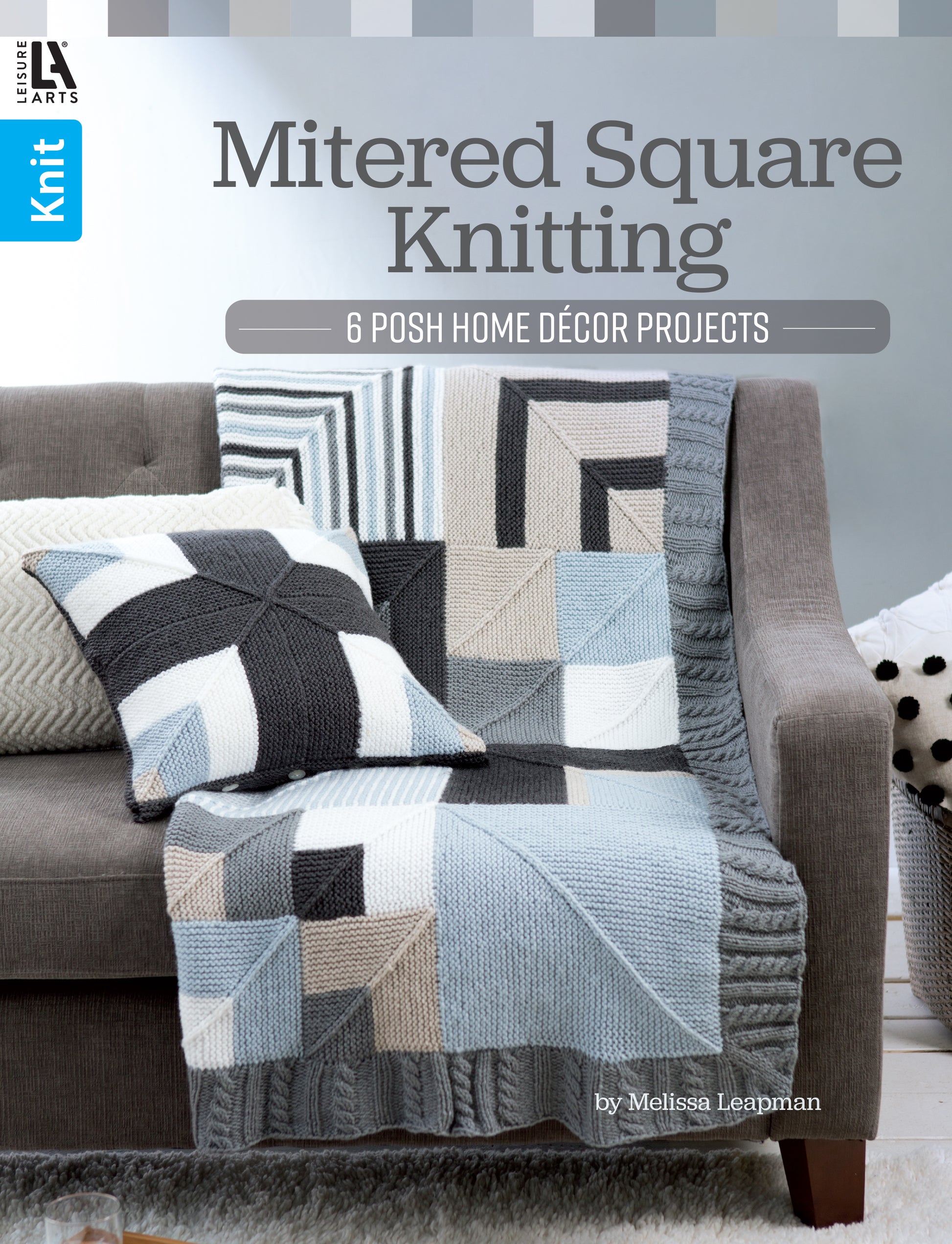 A gray sofa displays a black, white, gray, and beige mitered square knit pillow and matching garter stitch blanket draped over the armrest. The image is the cover for "Mitered Square Knitting Digital Download" by Leisure Arts.